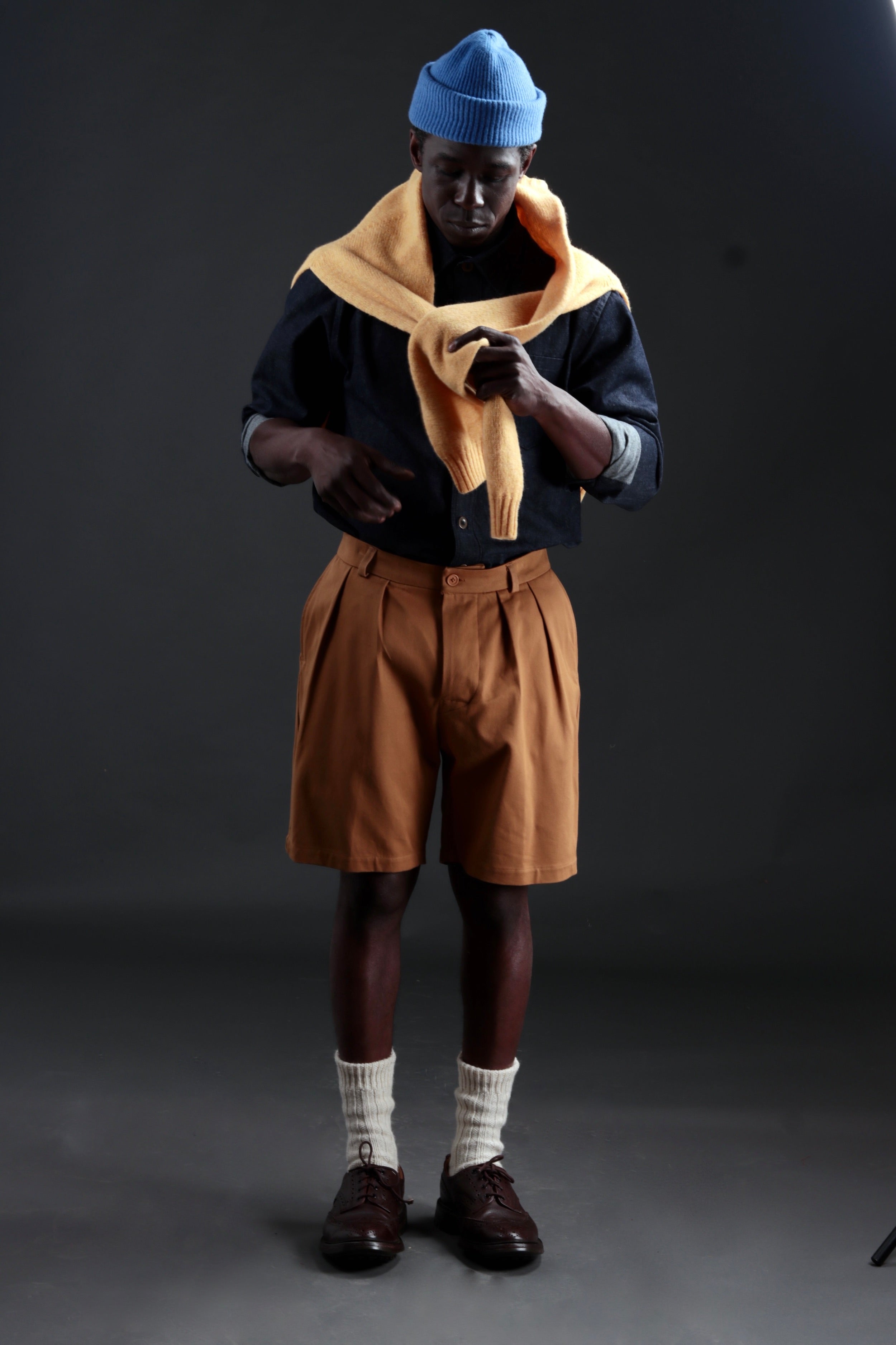 Abdul wears Carrier Company Grandpa Shorts in Tan with Denim Collar Shirt and Shetland Lambswool Jumper in Chamomile