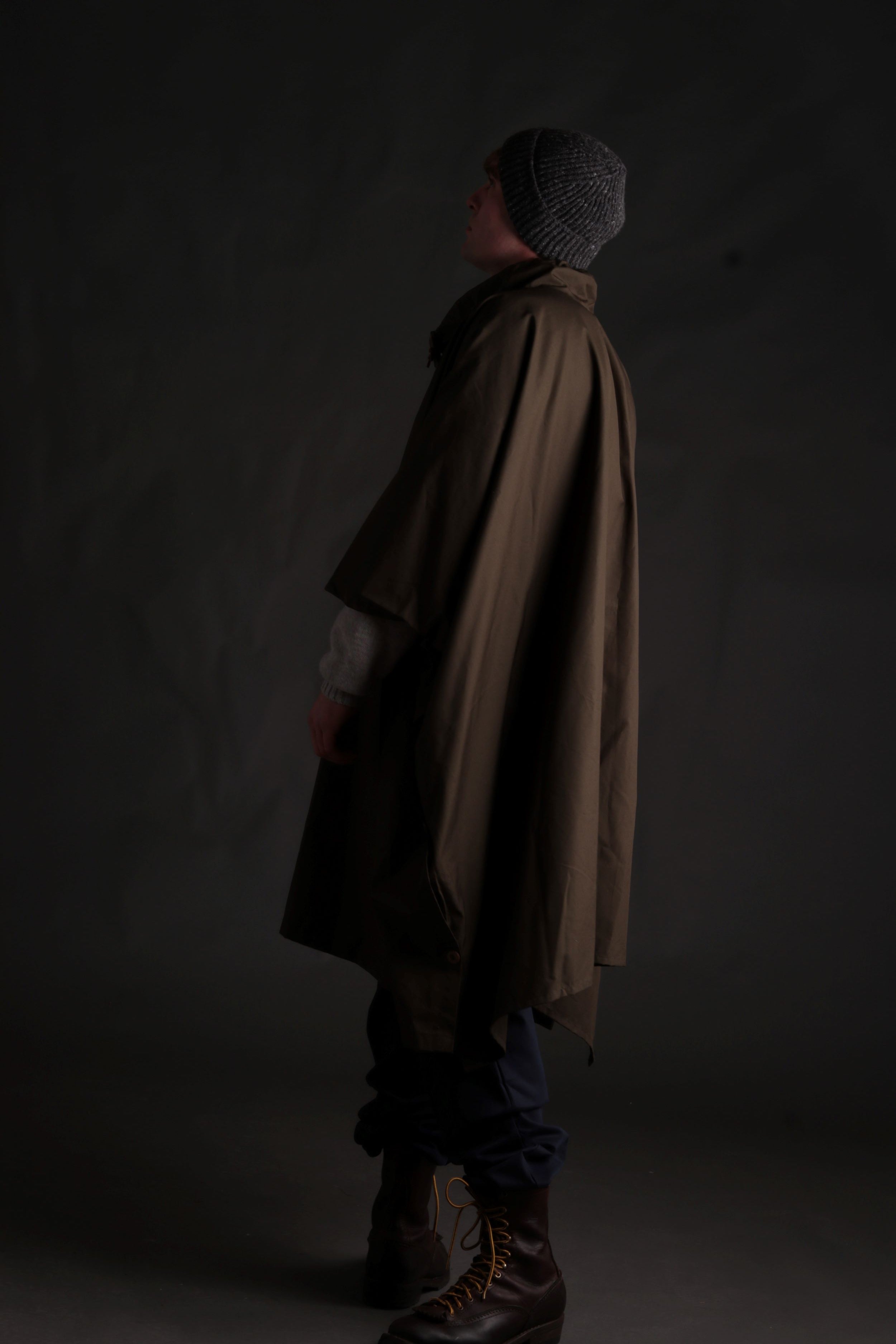 Man wears Long Rain Cape in Olive with Shetland Lambswool Jumper and Donegal Hat