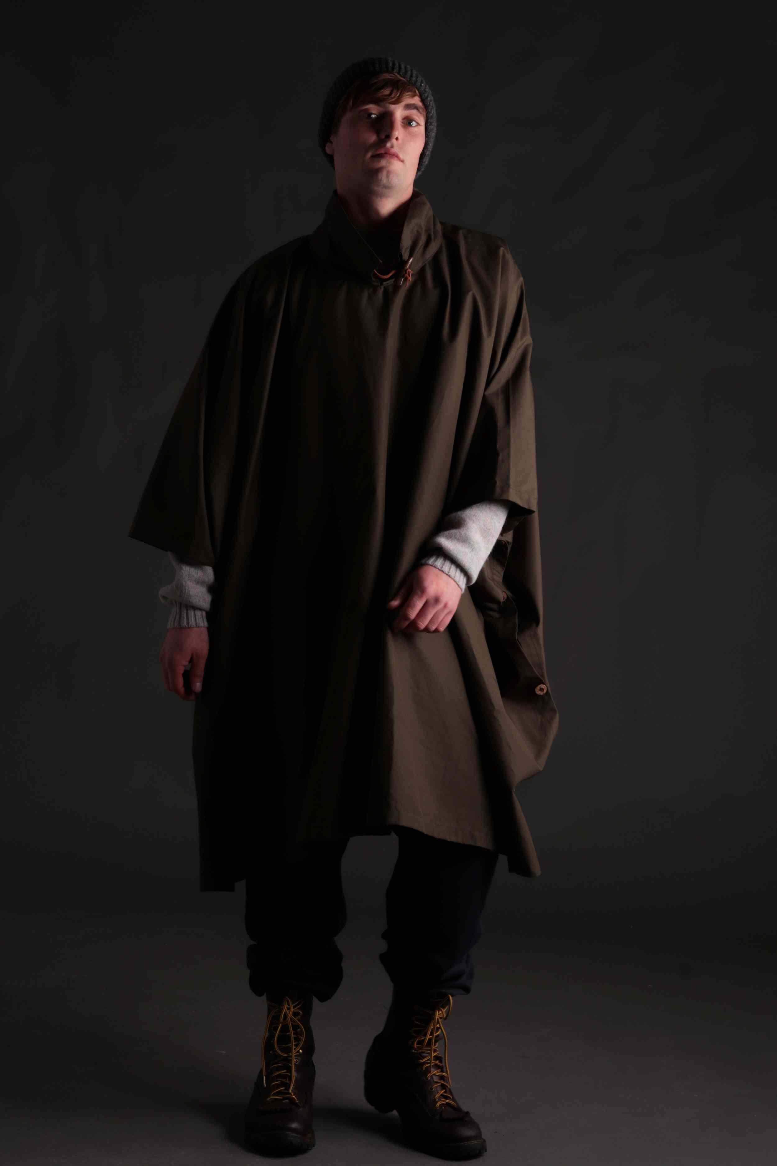 Man wears Long Rain Cape in Olive with Shetland Lambswool Jumper and Donegal Hat