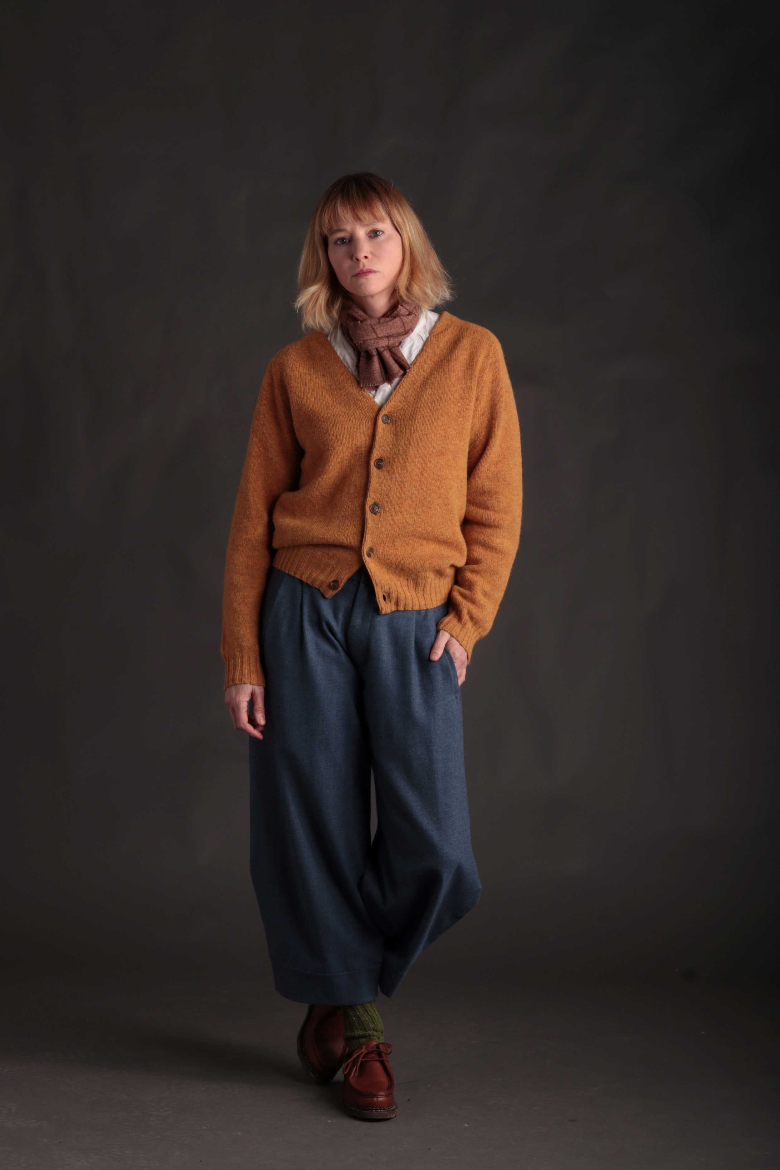 Woman wears Carrier Company Cardigan in Cumin with Dutch Trousers in Wool