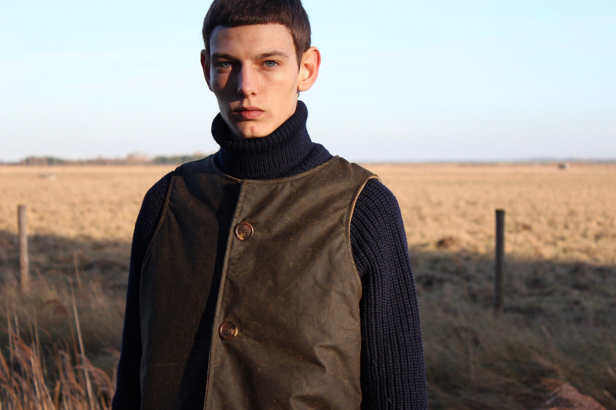 Man wearing Carrier Company Norfolk Jerkin in Dark Olive and Fisherman's Jumper