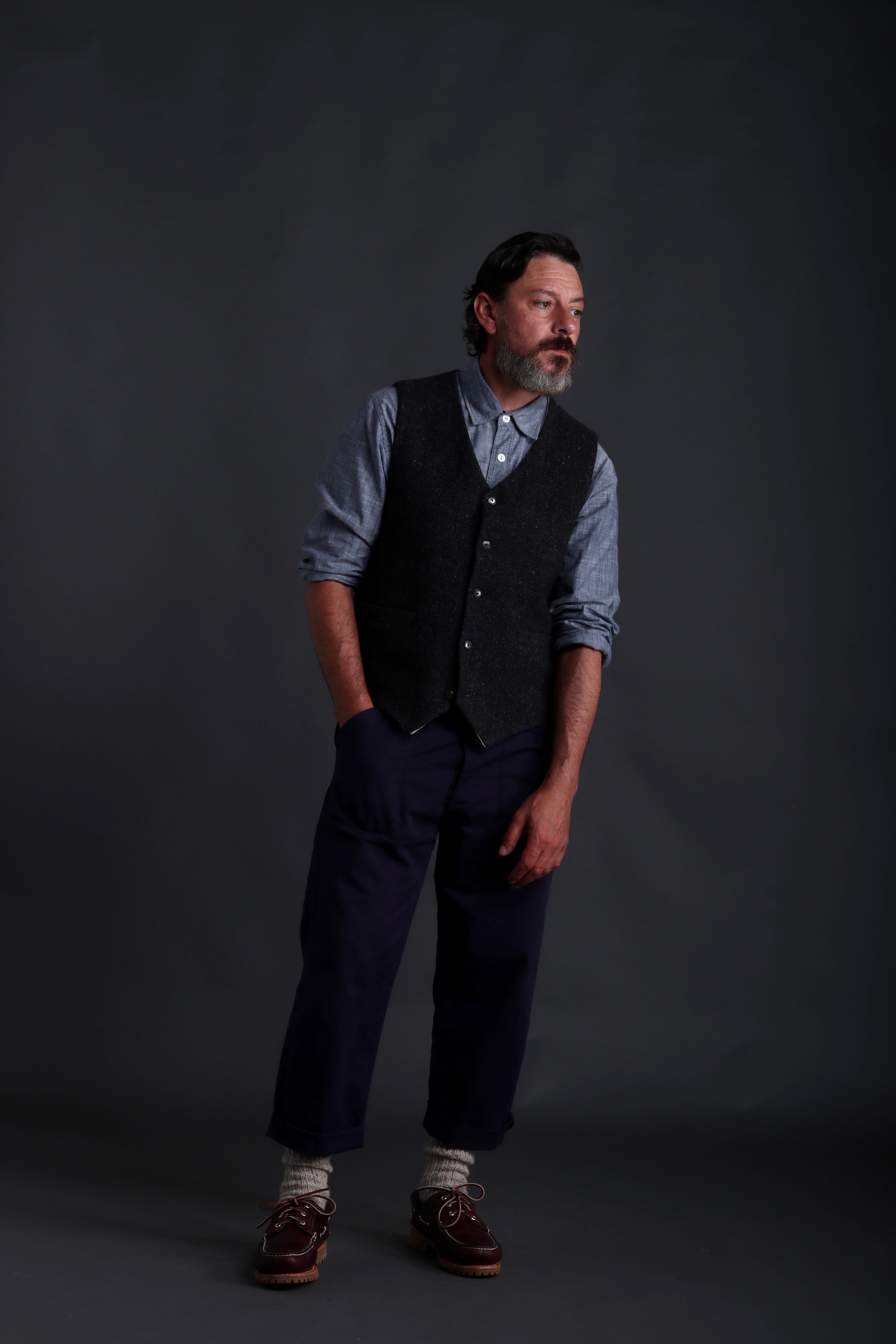 Man wears Carrier Company Men's Wool Waistcoat in Charcoal Herringbone