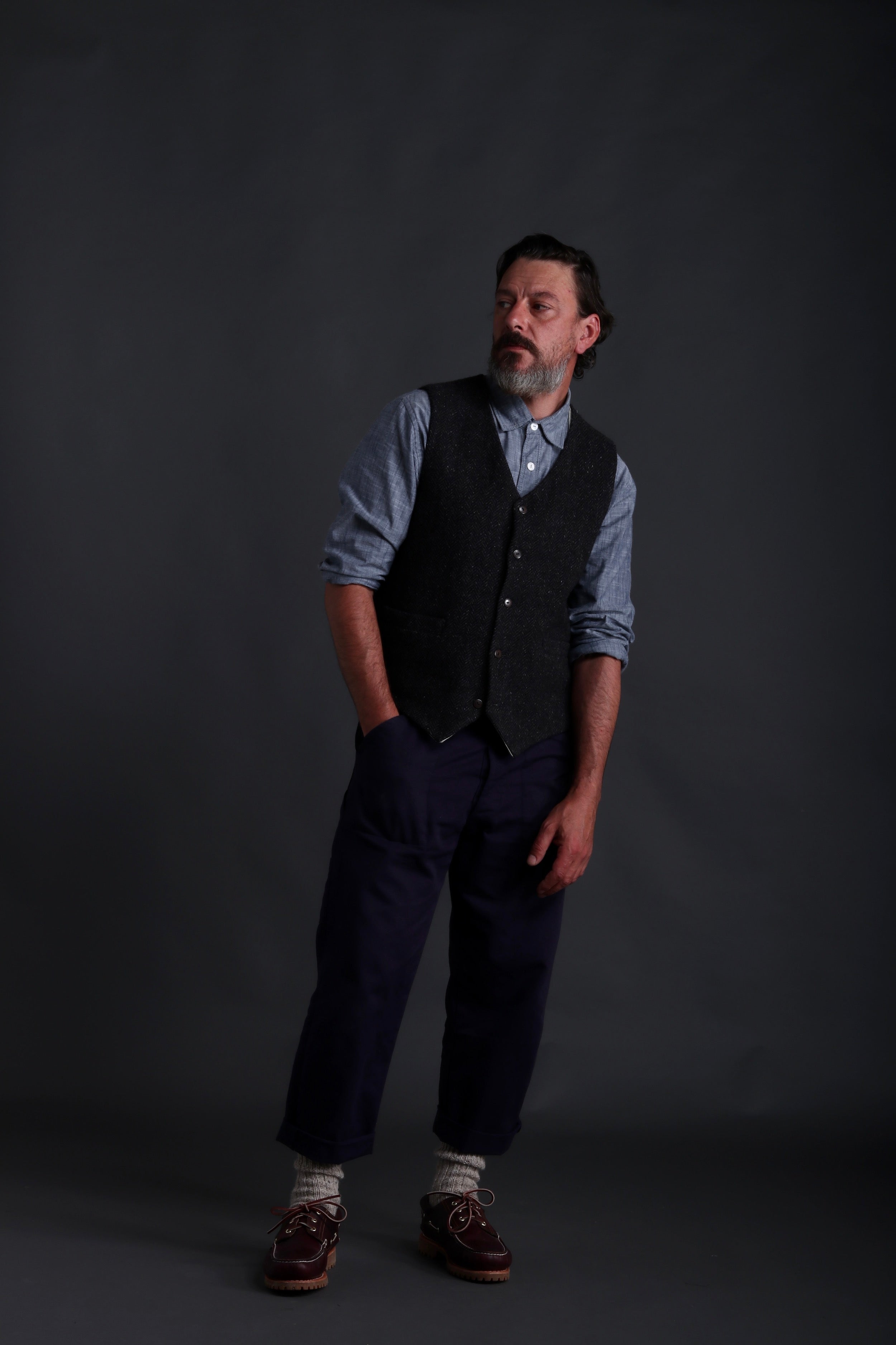 Man wears Carrier Company Men's Wool Waistcoat in Charcoal Herringbone