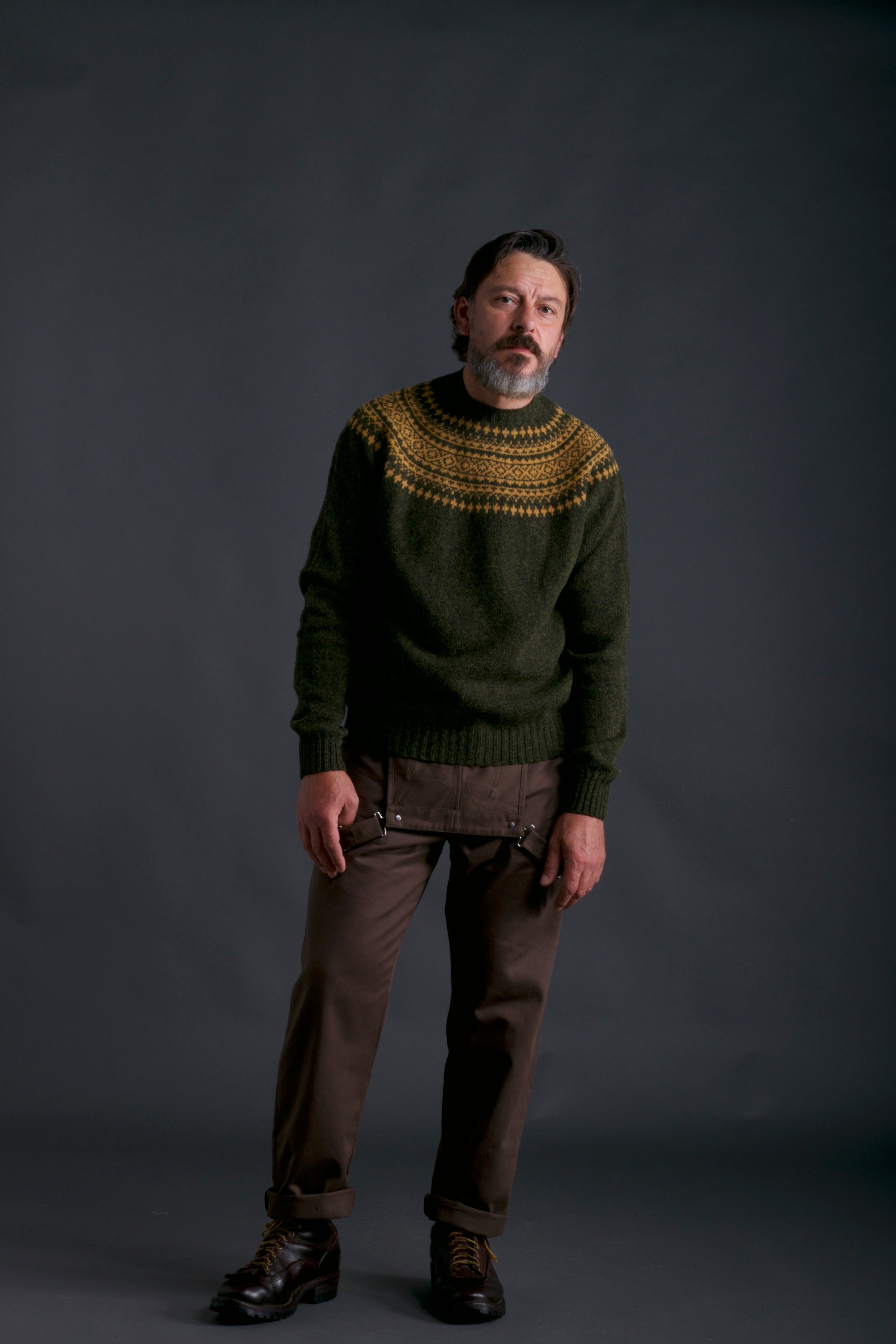 Man wears Carrier Company Shetland Yoke Jumper in Kale & Mustard with Olive Men's Dungarees