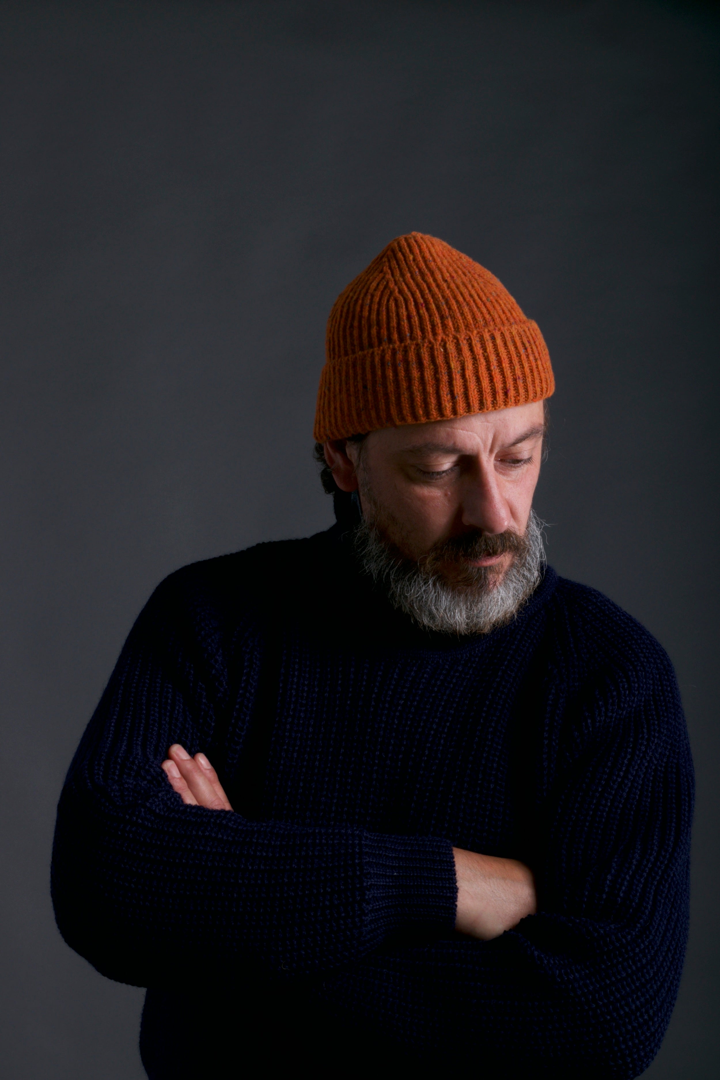 Man wears Carrier Company Donegal Wool Hat in Tangerine with Navy Fisherman's Jumper