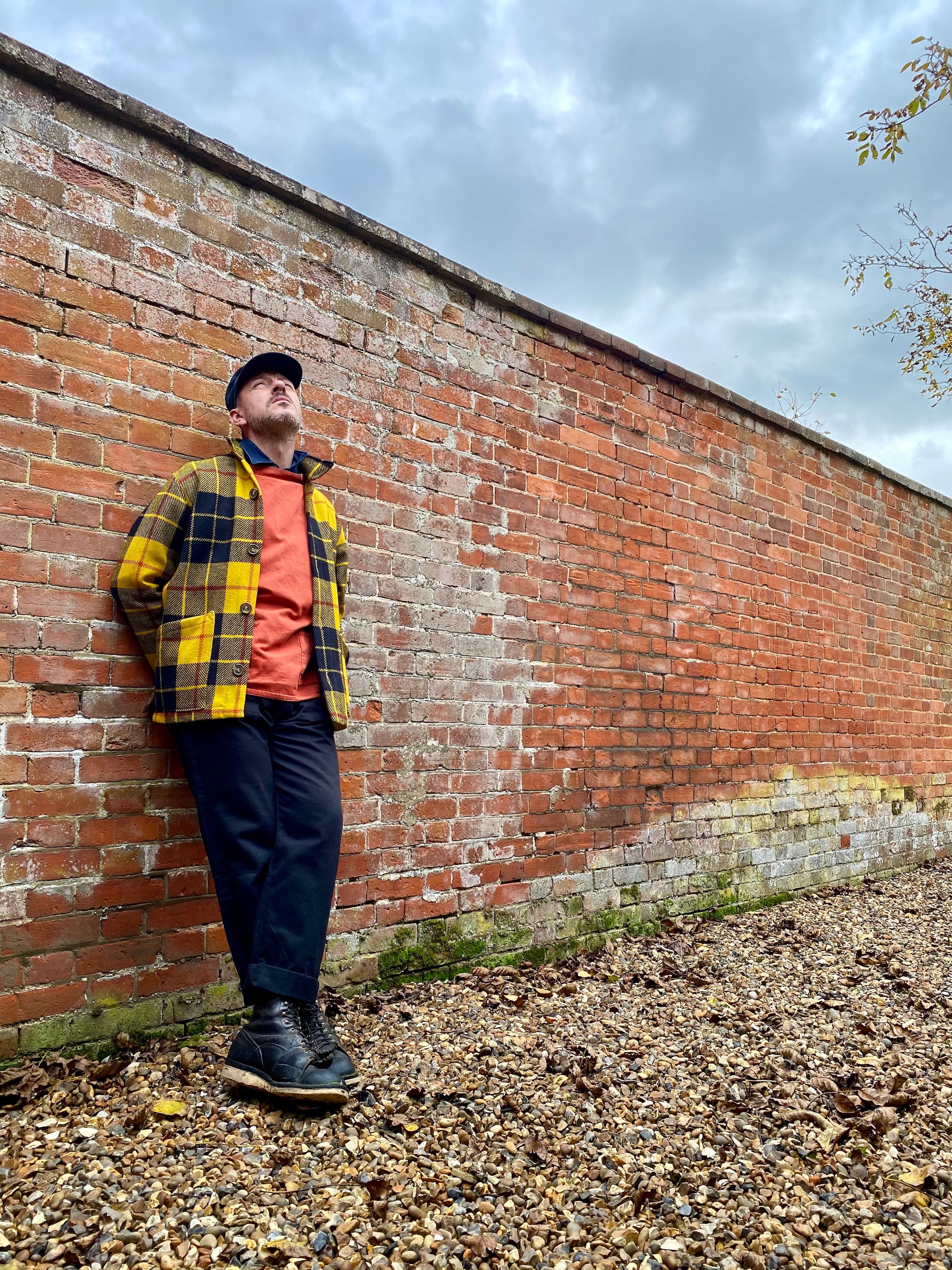 Man wearing Carrier Company Traditional Norfolk slop in Orange with Celtic wool Jacket and Black Dungarees and Denim Collar Shirt