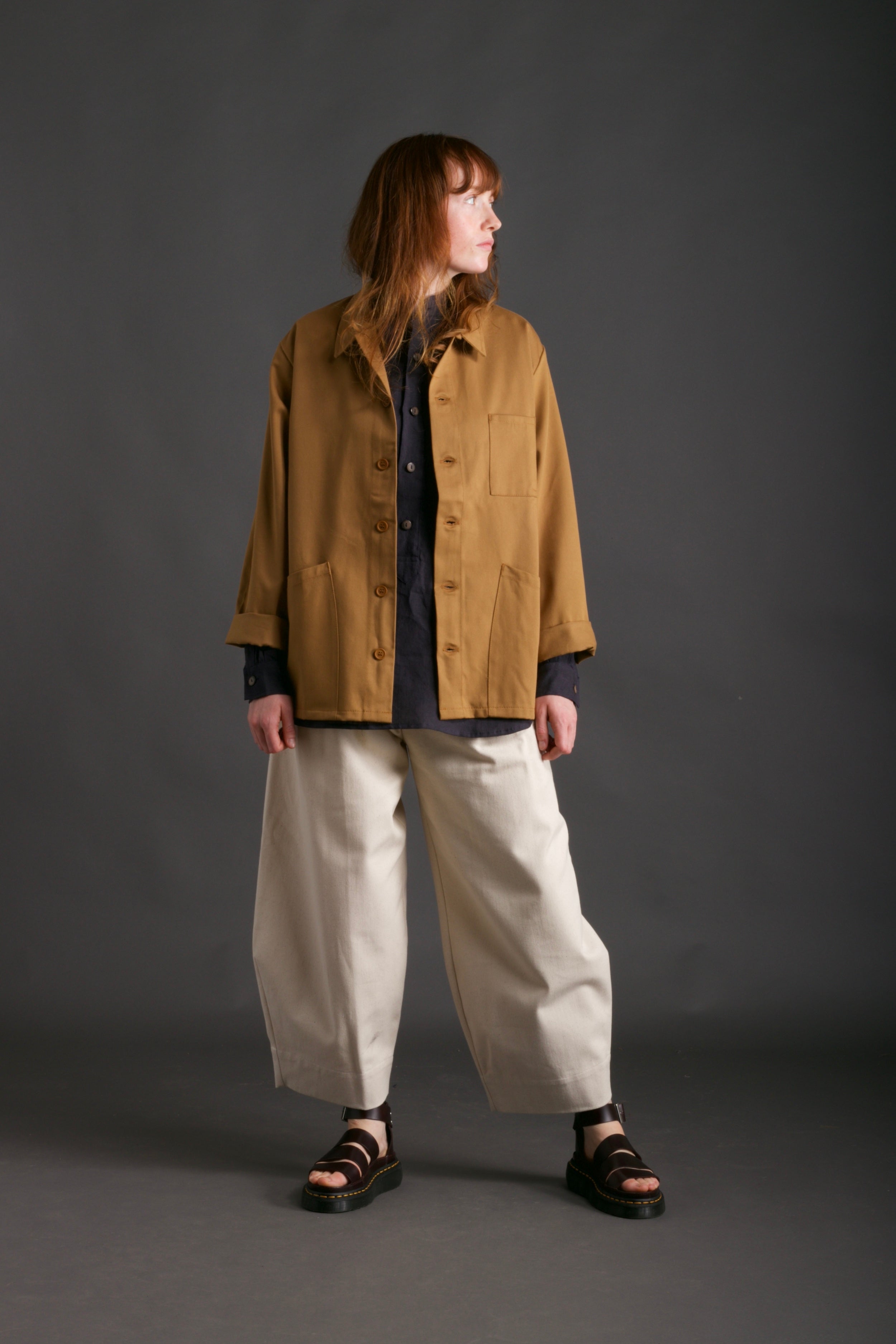 Woman wears Carrier Company Work Jacket in Tan with Dutch Trouser in Seeded Denim and Collarless Work Shirt in Navy Linen