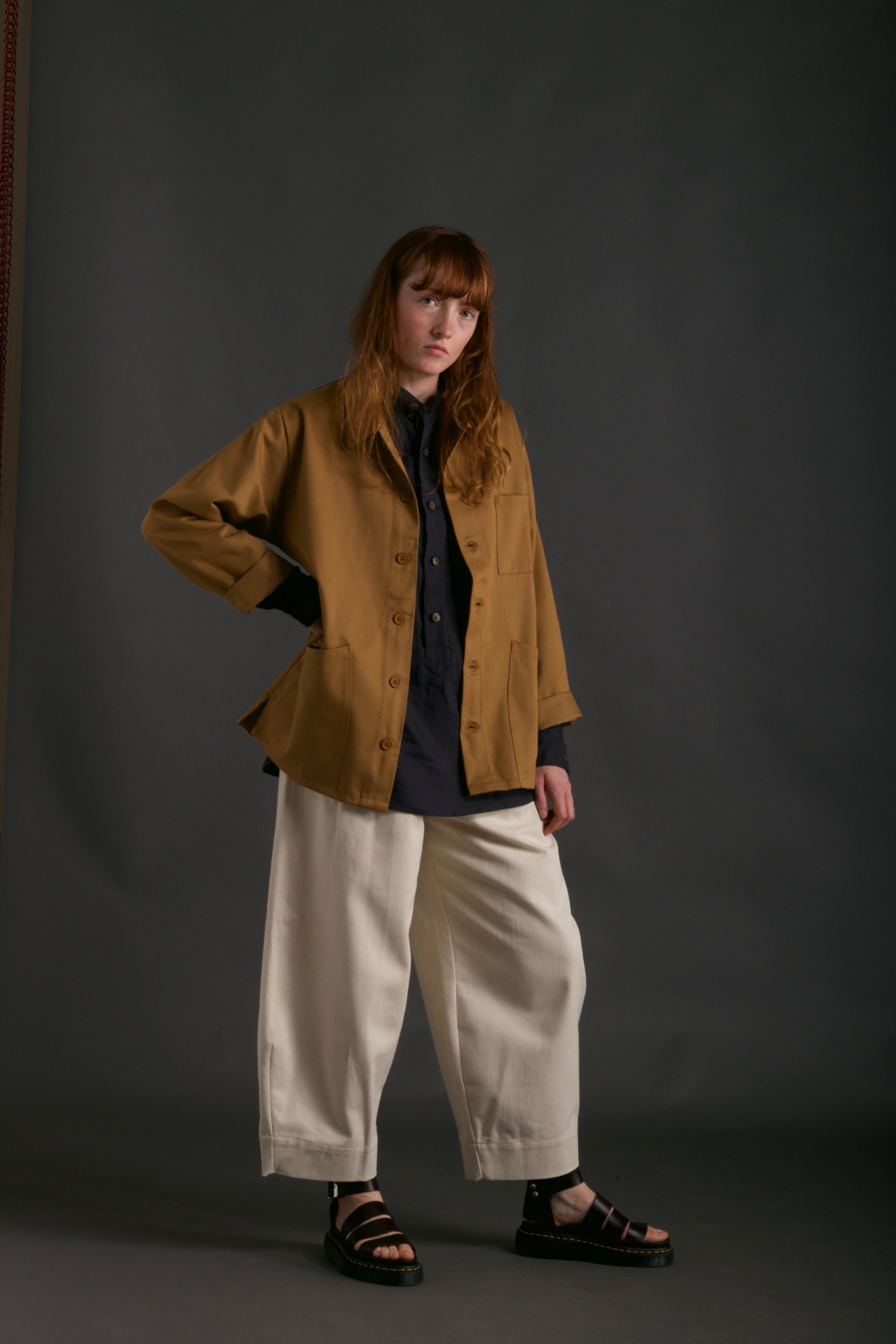 Woman wears Carrier Company Work Jacket in Tan with Dutch Trouser in Seeded Denim and Collarless Work Shirt in Navy Linen