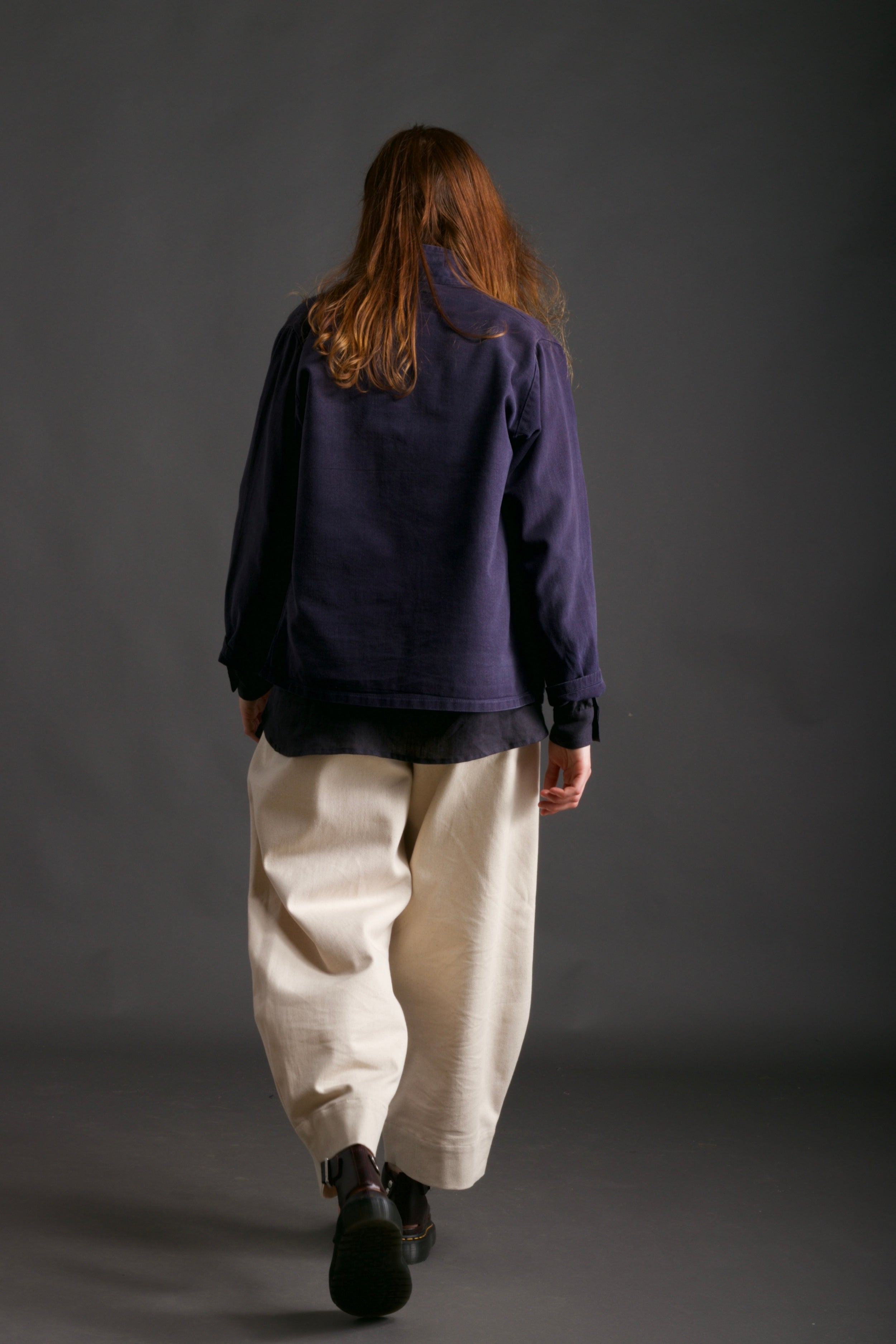 Woman wearing Carrier Company Traditional Norfolk Work Jacket in Navy with Dutch Trouser in Seeded Denim and  Collarless Work Shirt in Navy Linen