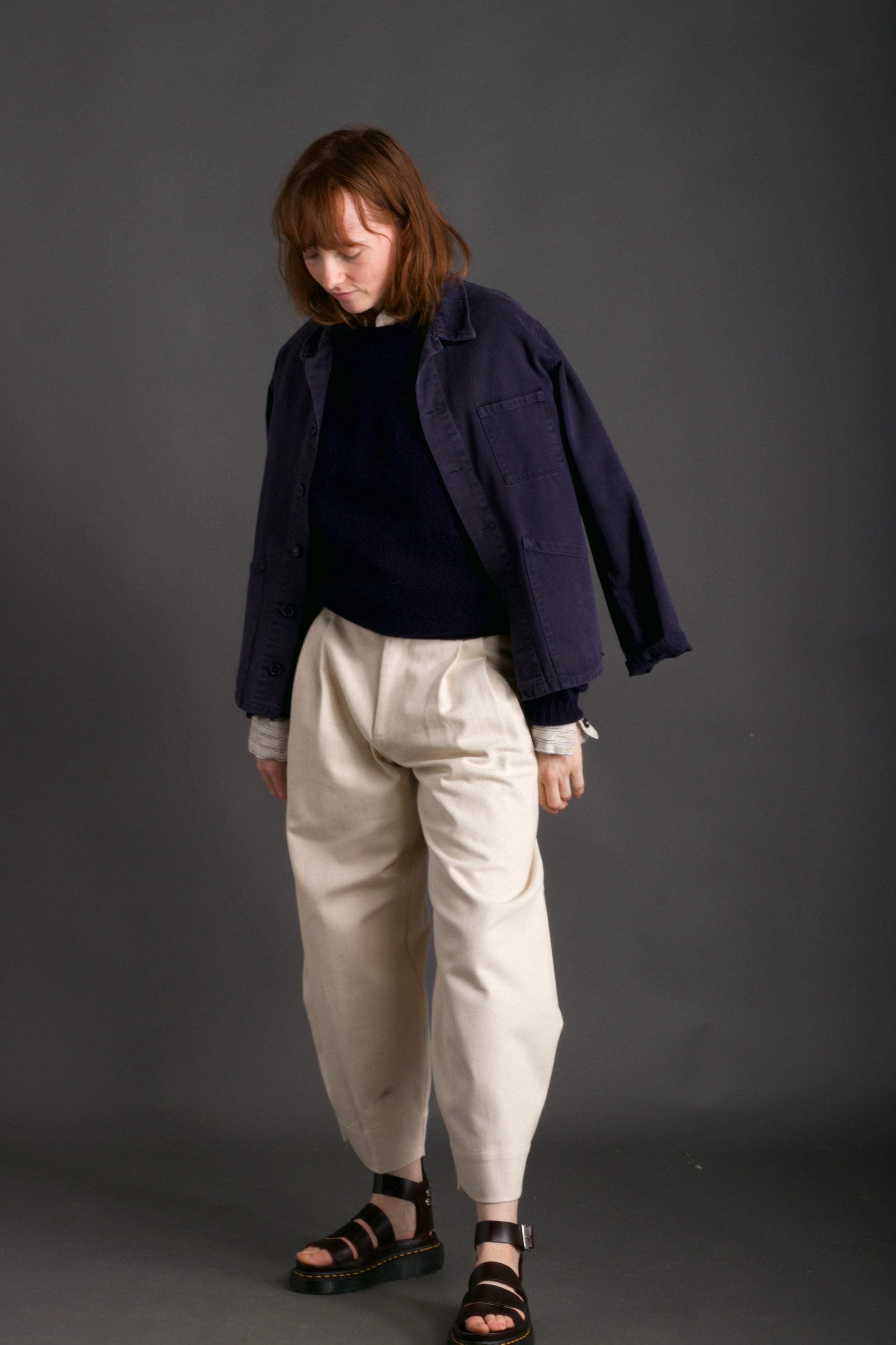 Woman wears Carrier Company Shetland Lambswool Jumper in Navy with Dutch Trouser in Seeded Denim and Norfolk Work Jacket