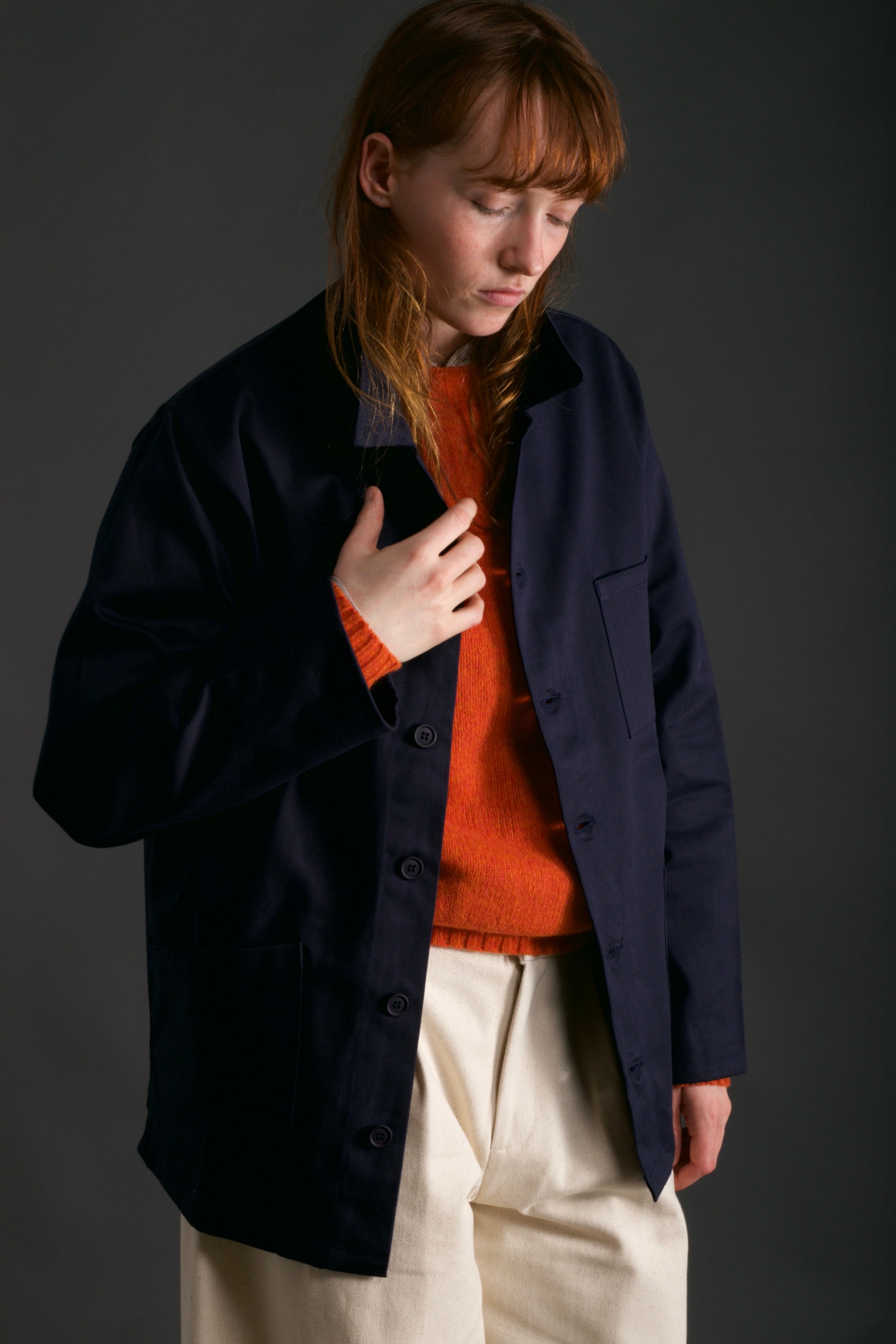 Woman wearing Carrier Company Traditional Norfolk Work Jacket in Navy with Dutch Trouser in Seeded Denim and Shetland Lambswool Jersey in Tangerine