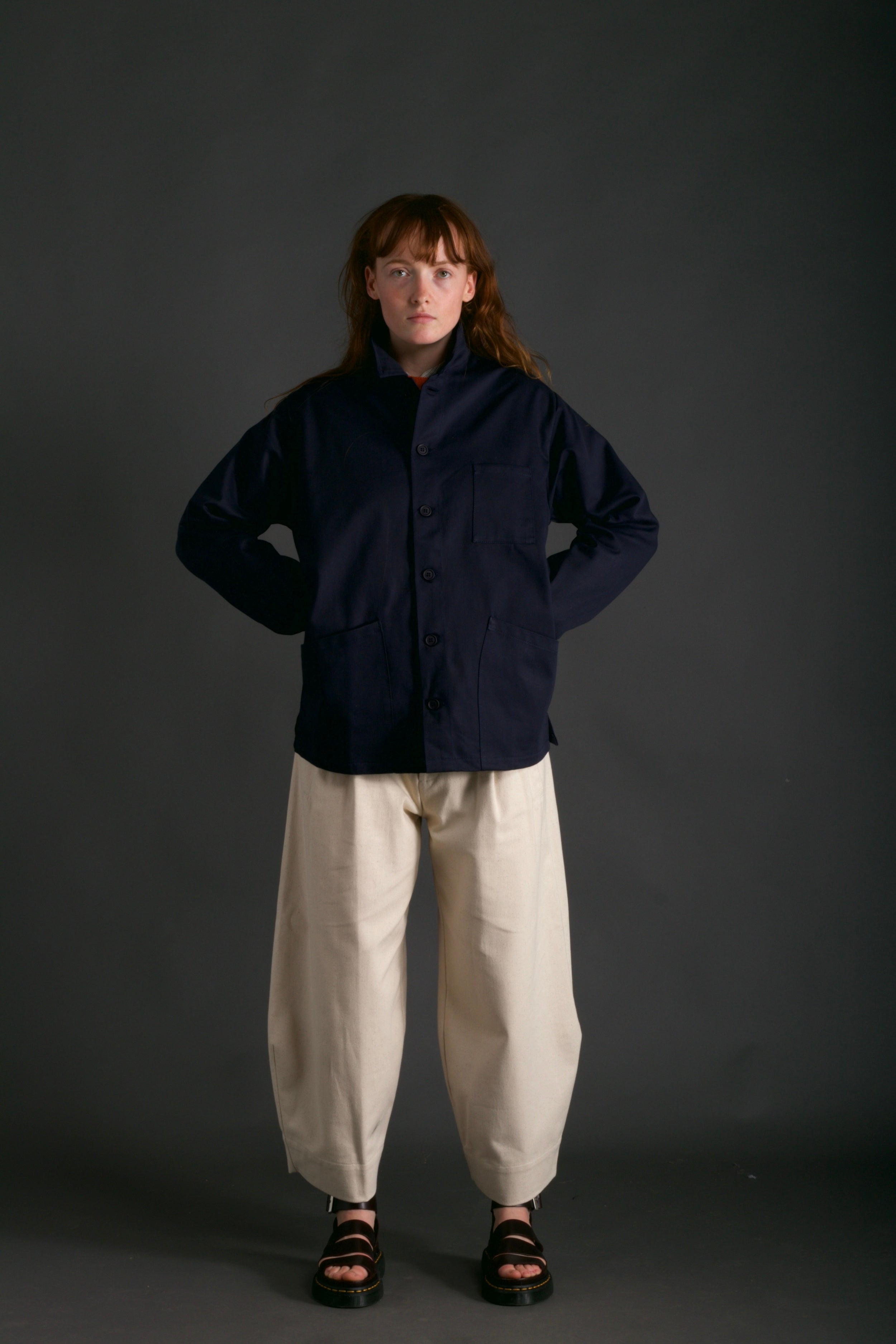Woman wearing Carrier Company Traditional Norfolk Work Jacket in Navy with Dutch Trouser in Seeded Denim and Shetland Lambswool Jersey in Tangerine