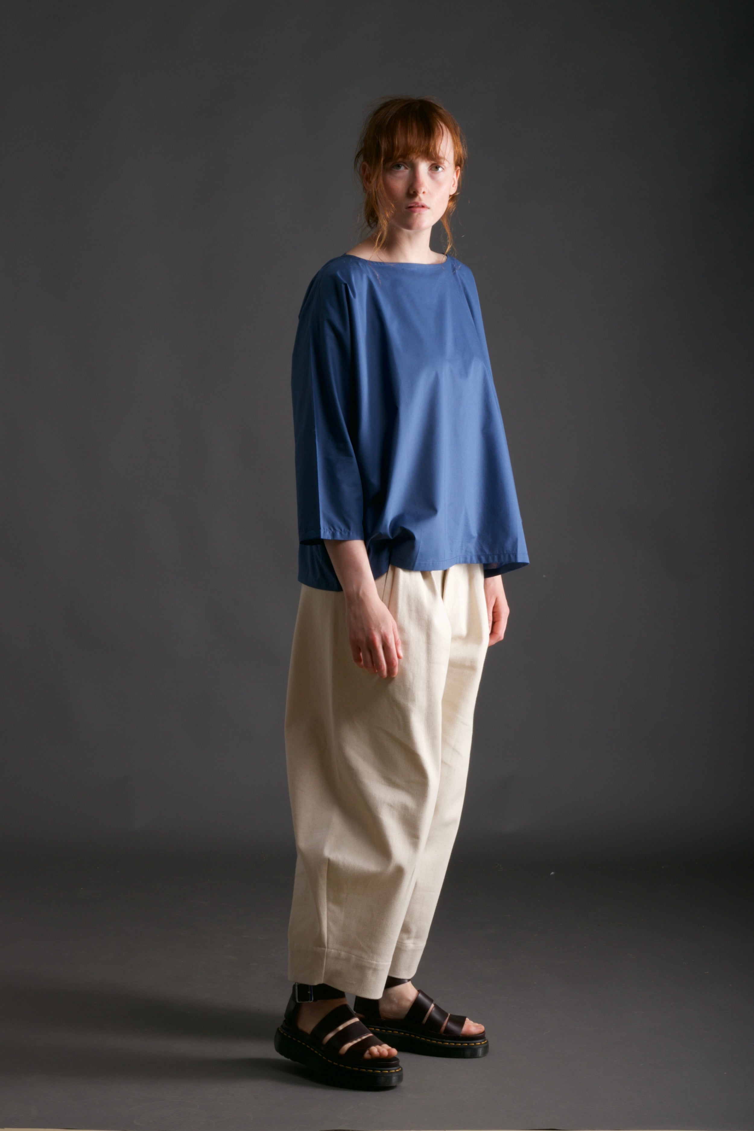 Woman wears Carrier Company Cotton Tee Shirt in Petrol Blue with Dutch Trouser in Seeded Denim