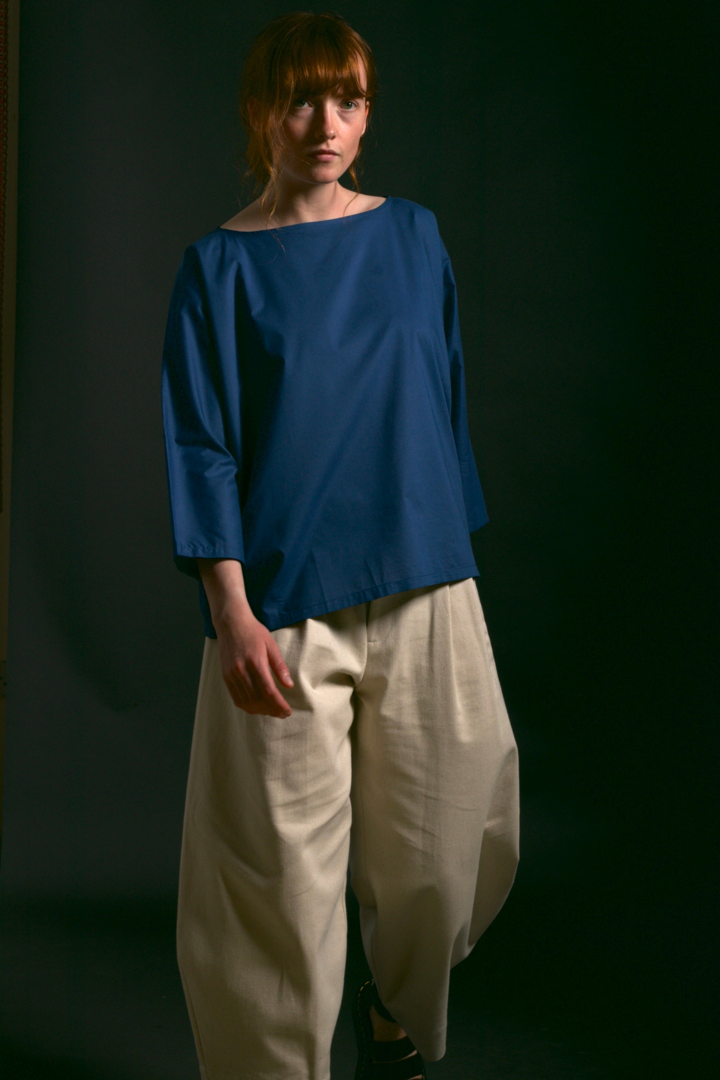 Woman wears Carrier Company Cotton Tee Shirt in Petrol Blue with Dutch Trouser in Seeded Denim