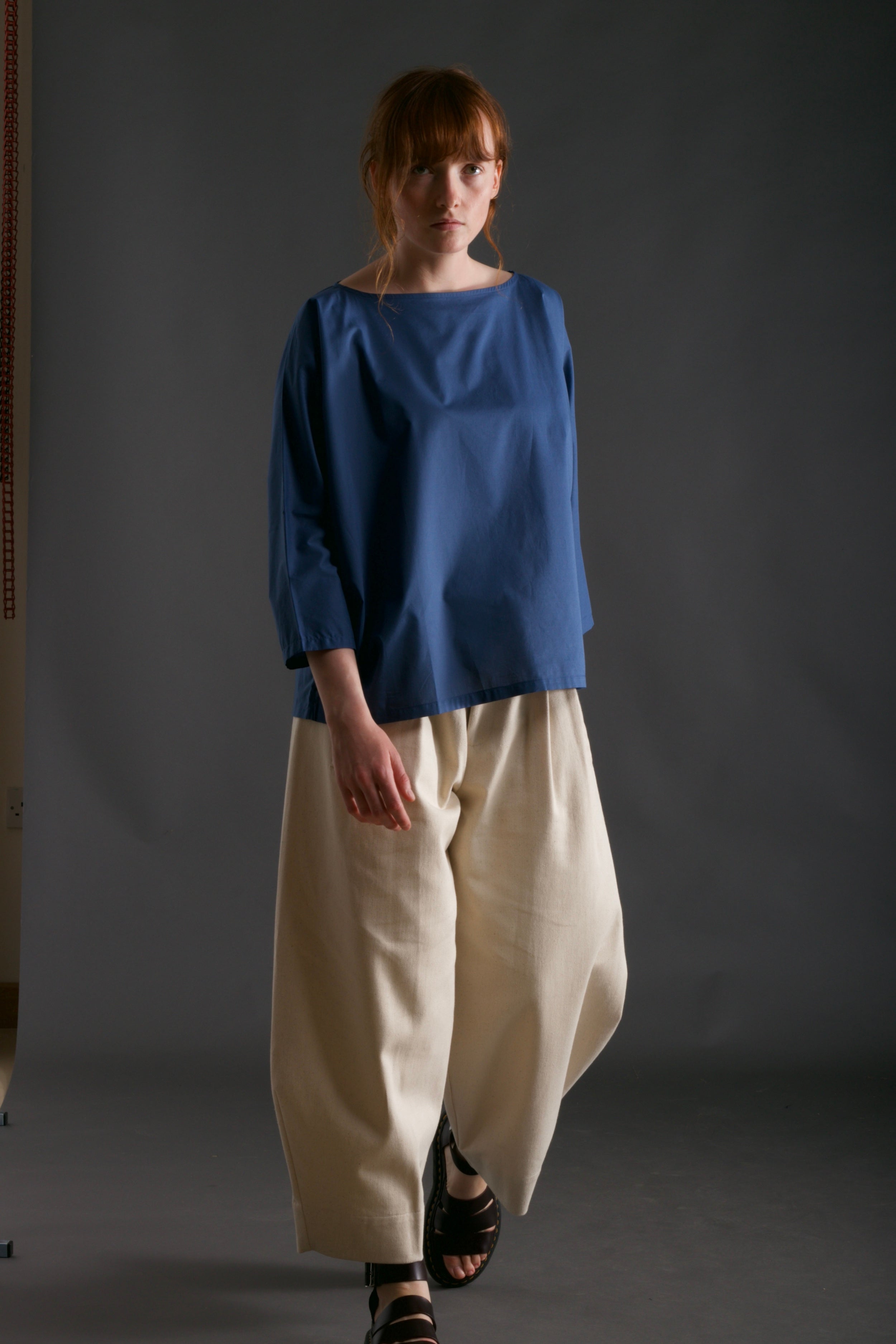 Woman wears Carrier Company Cotton Tee Shirt in Petrol Blue with Dutch Trouser in Seeded Denim