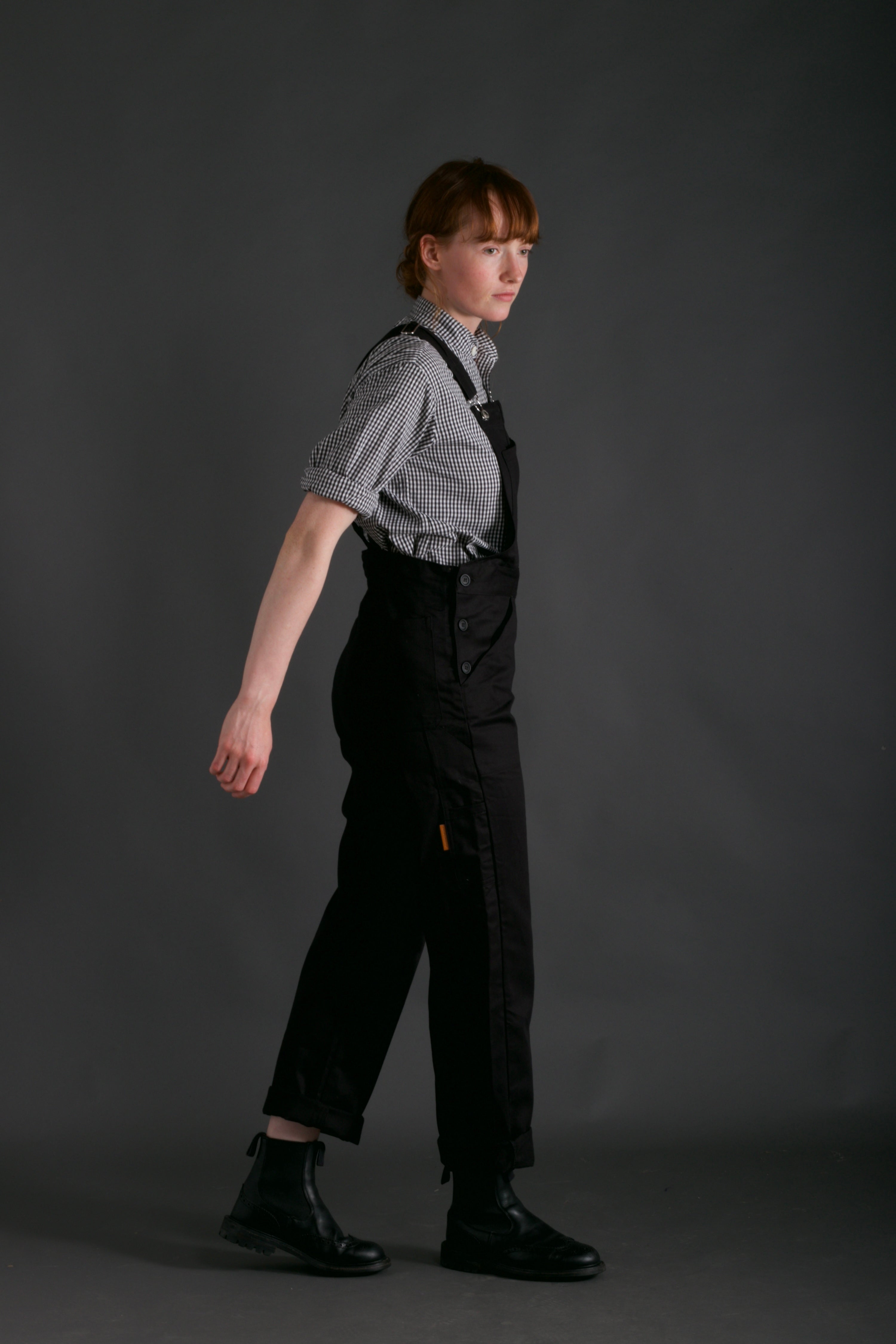 Woman wears Carrier Company Women's Dungarees and Organic Cotton Collarless Shirt in Black Gingham