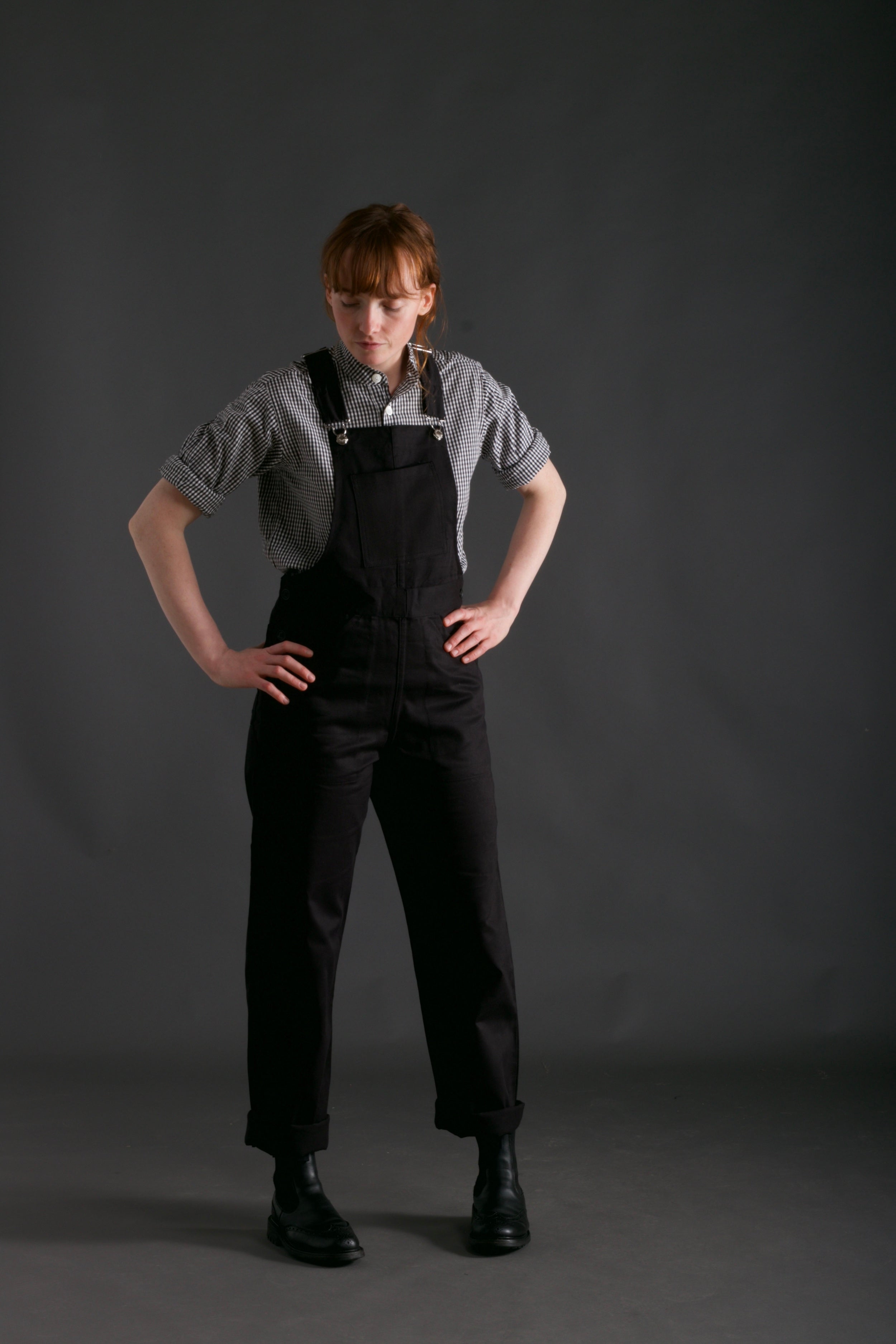 Woman wears Carrier Company Women's Dungarees and Organic Cotton Collarless Shirt in Black Gingham