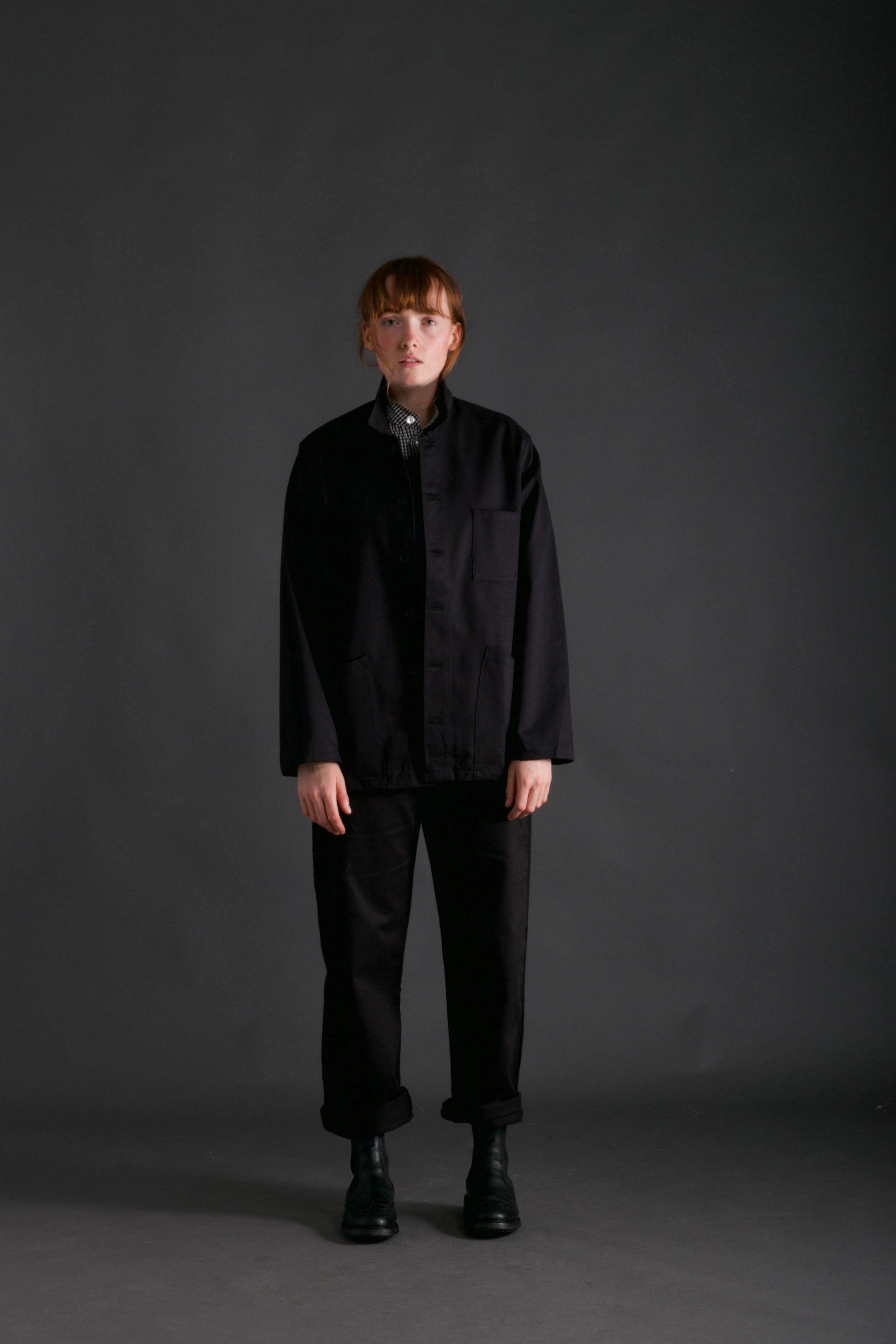 Woman wears Carrier Company Norfolk Work jacket in Black with Women's Dungarees and Organic Cotton Collarless Shirt in Black Gingham