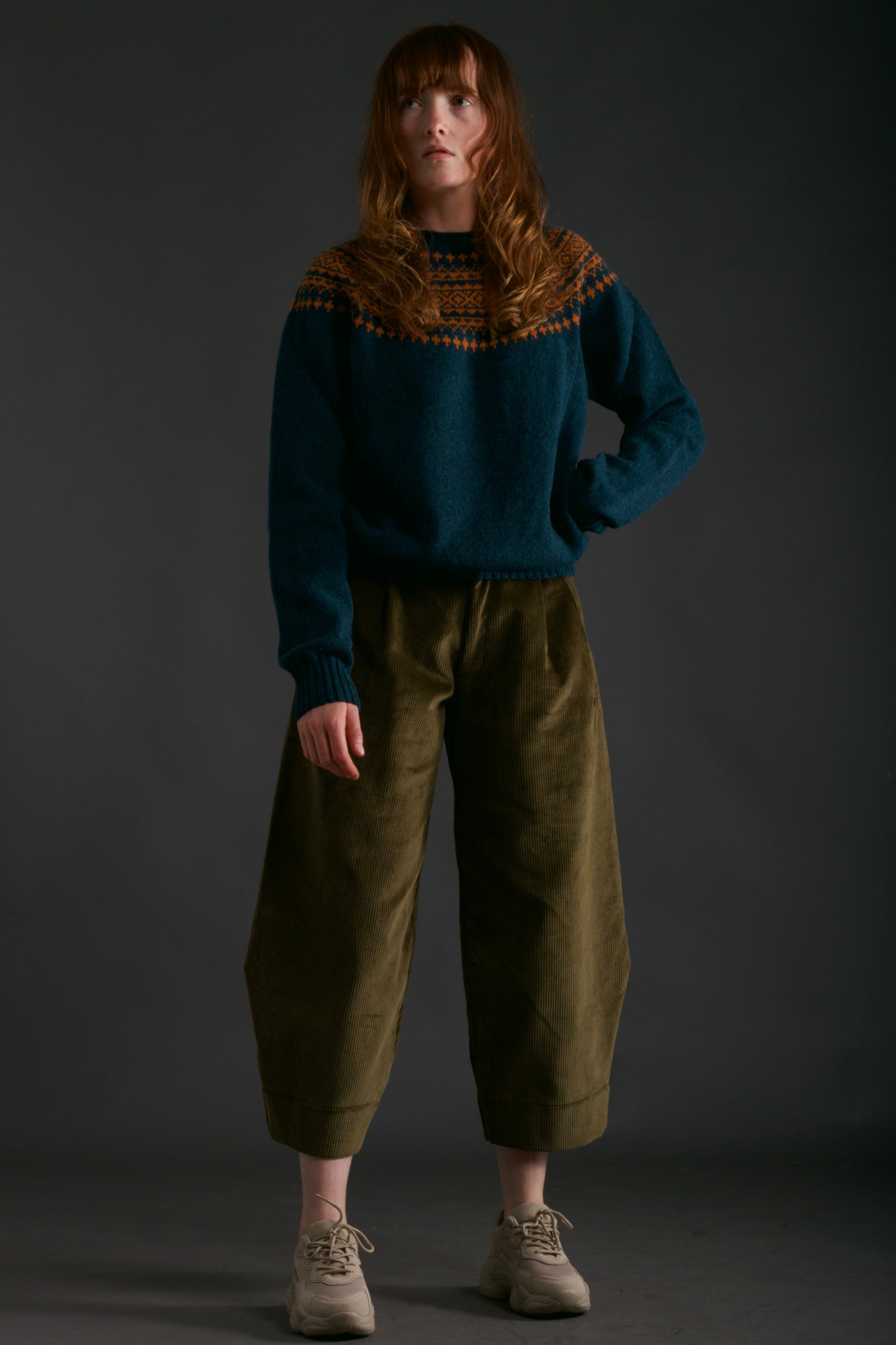 Woman wears Carrier Company Shetland Yoke Jumper in ginger and Teal with Dutch Trouser in Corduroy