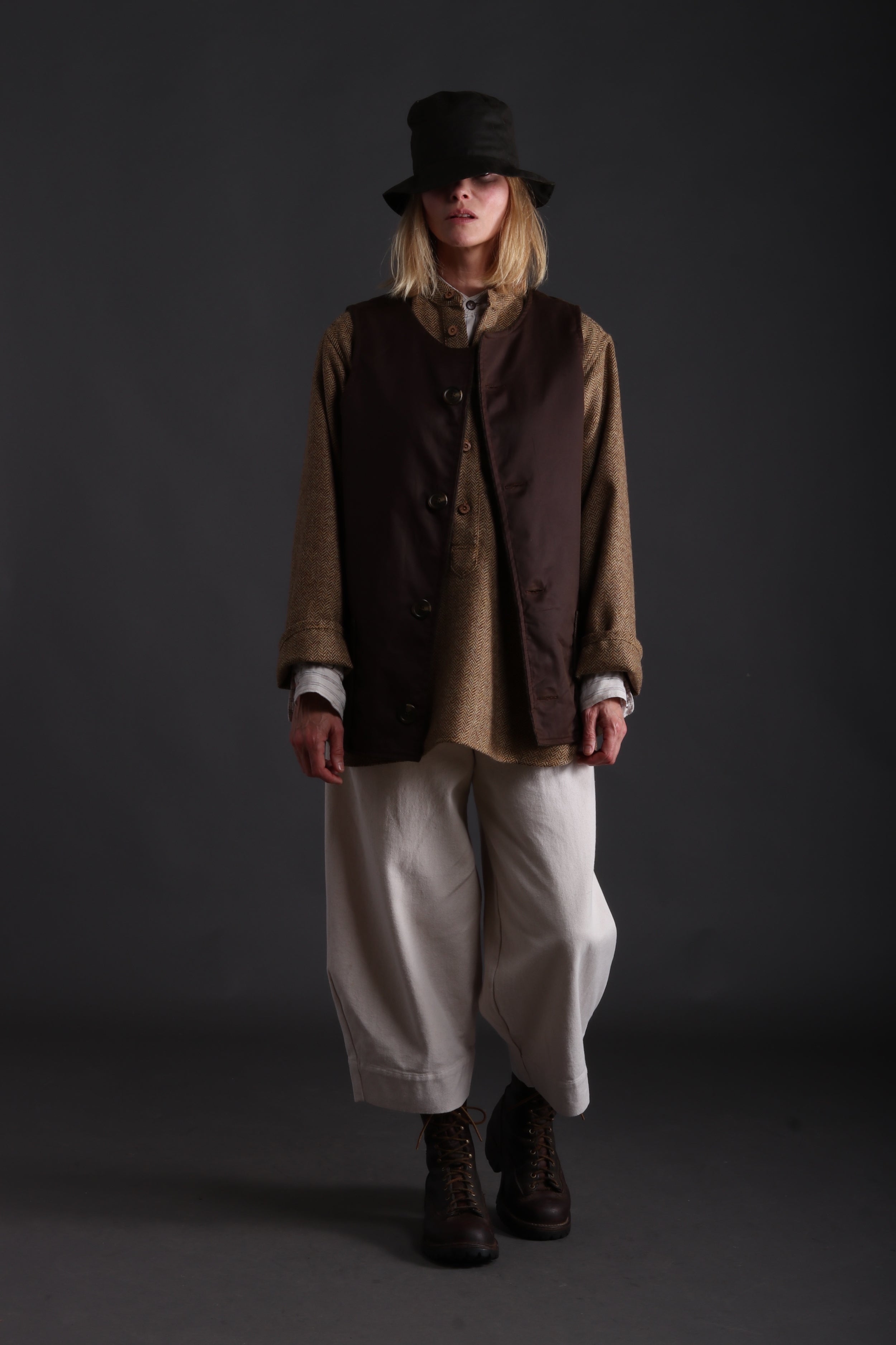 Woman wears Dutch Trouser in Seeded Denim with Wool Overhshirt, Linen Collarless Workshirt and Traditional Norfolk Jerkin