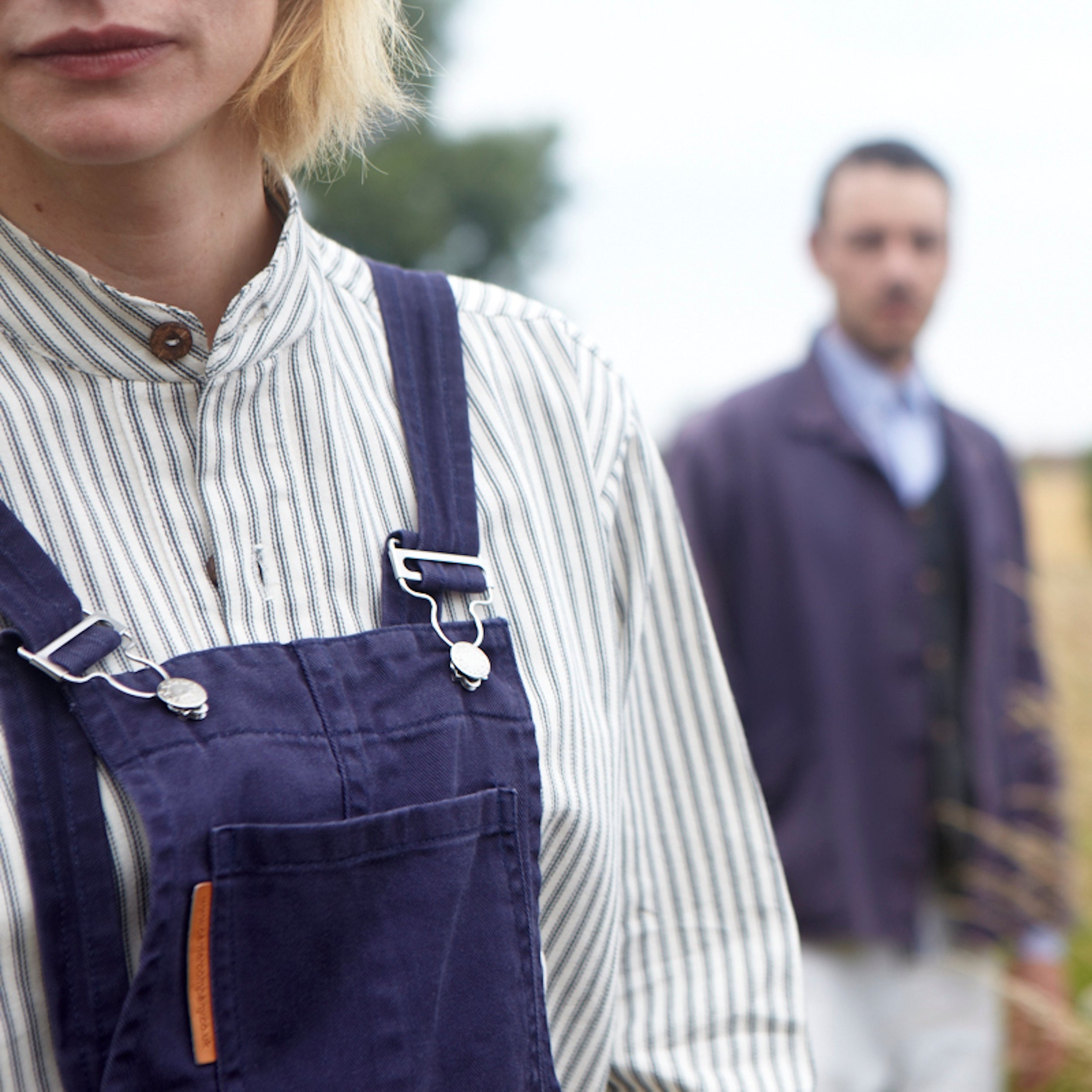 Woman wears Carrier Company Women's Dungarees in Navy with Ticking Work Shirt