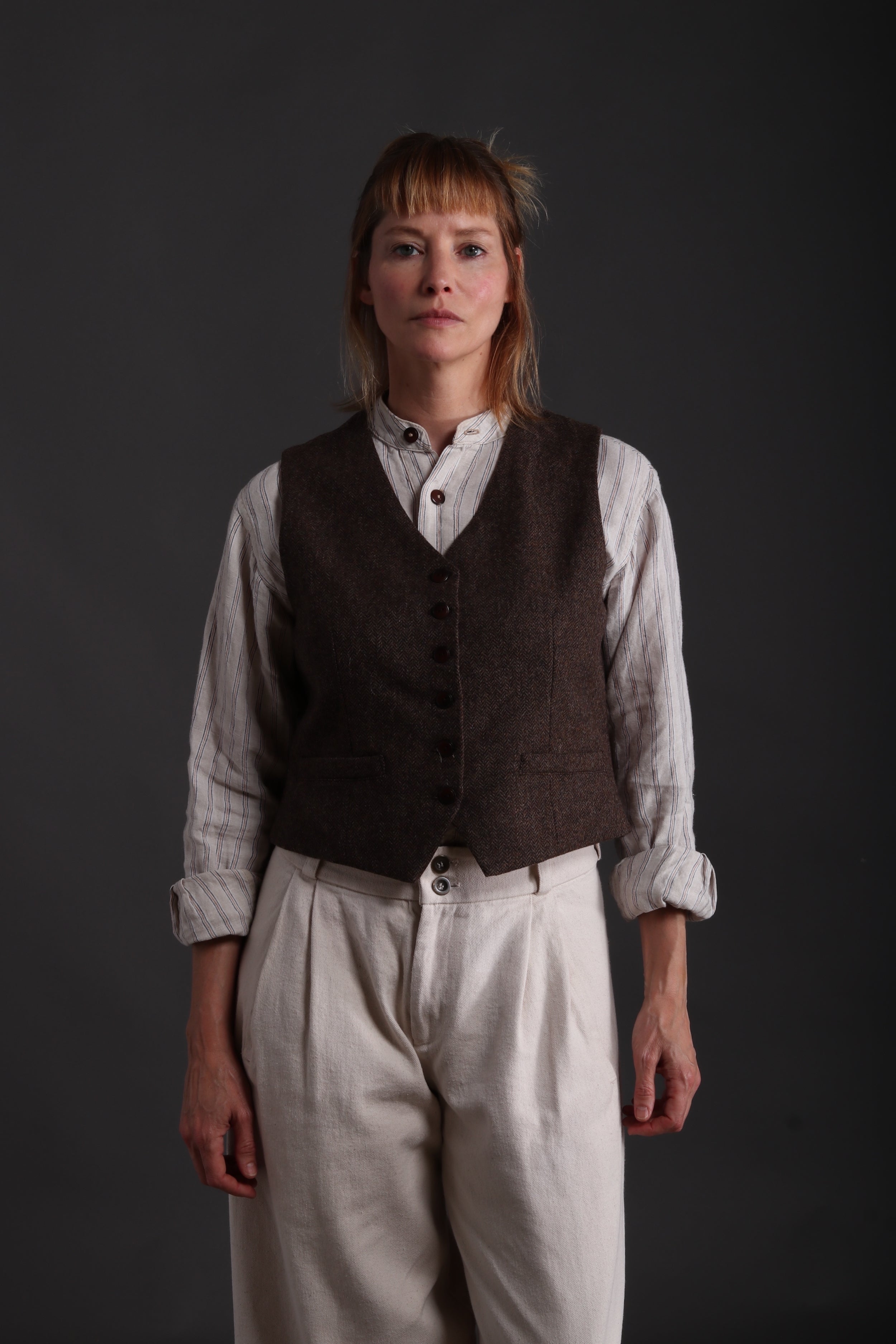 Woman wears Carrier Company Women's Wool Waistcoat in brown with Linen Collarless Worksheet and Dutch trouser in Seeded Denim