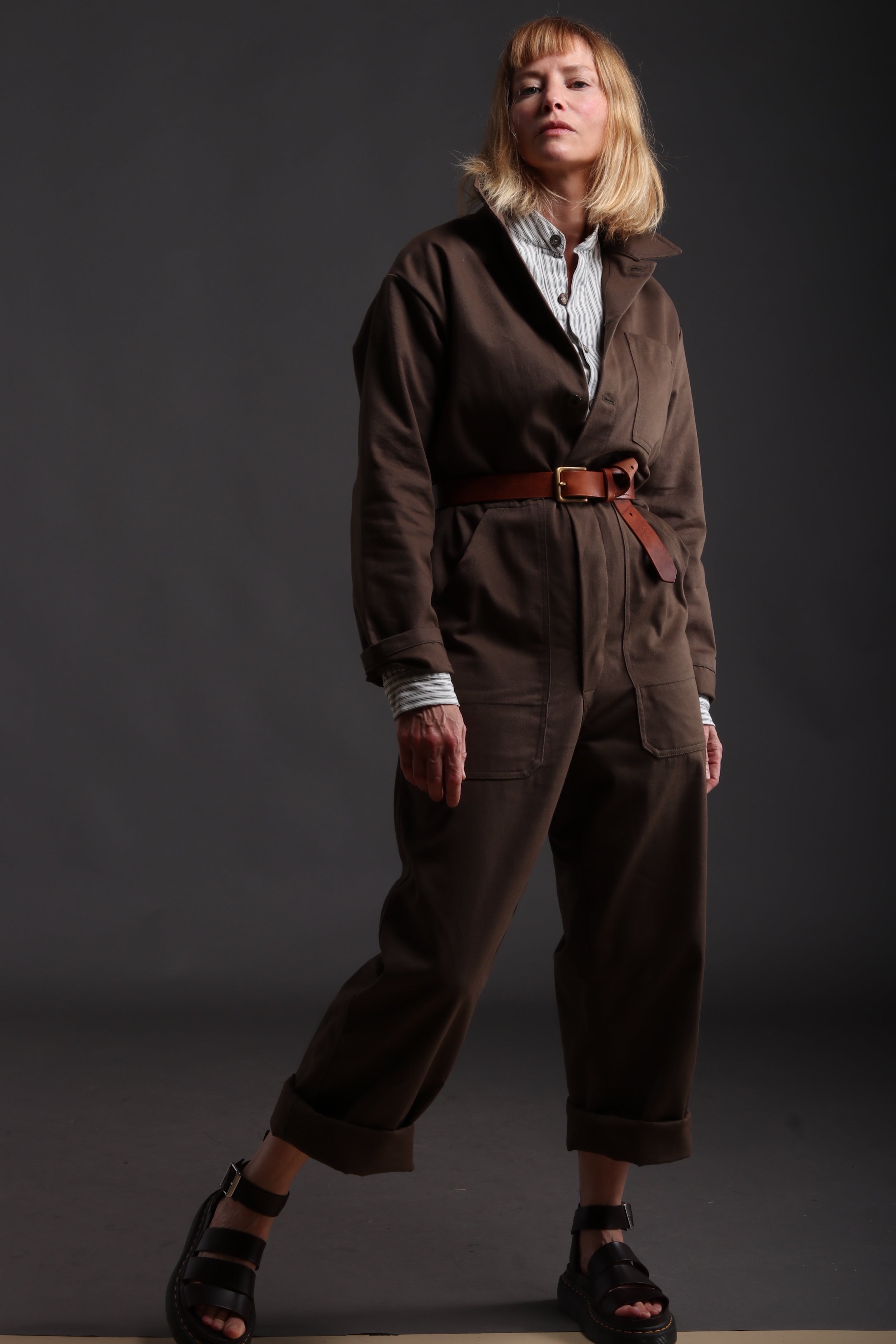 Sienna wears Carrier Company Boiler Suit in Olive Drill with Collarless Work Shirt in Ticking, Wool Hat and Chestnut Leather Belt