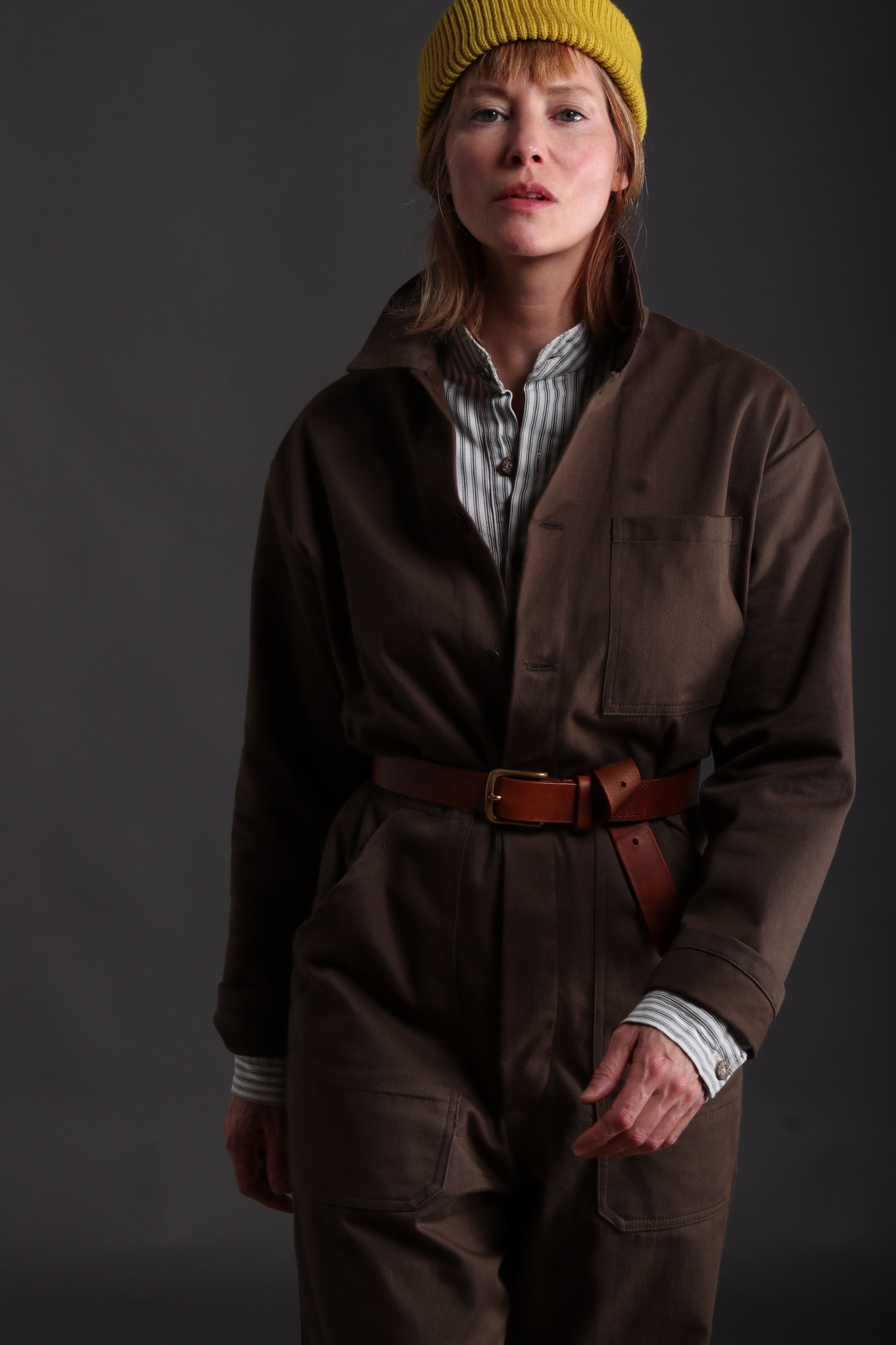 Sienna wears Carrier Company Boiler Suit in Olive Drill with Collarless Work Shirt in Ticking, Wool Hat and Chestnut Leather Belt
