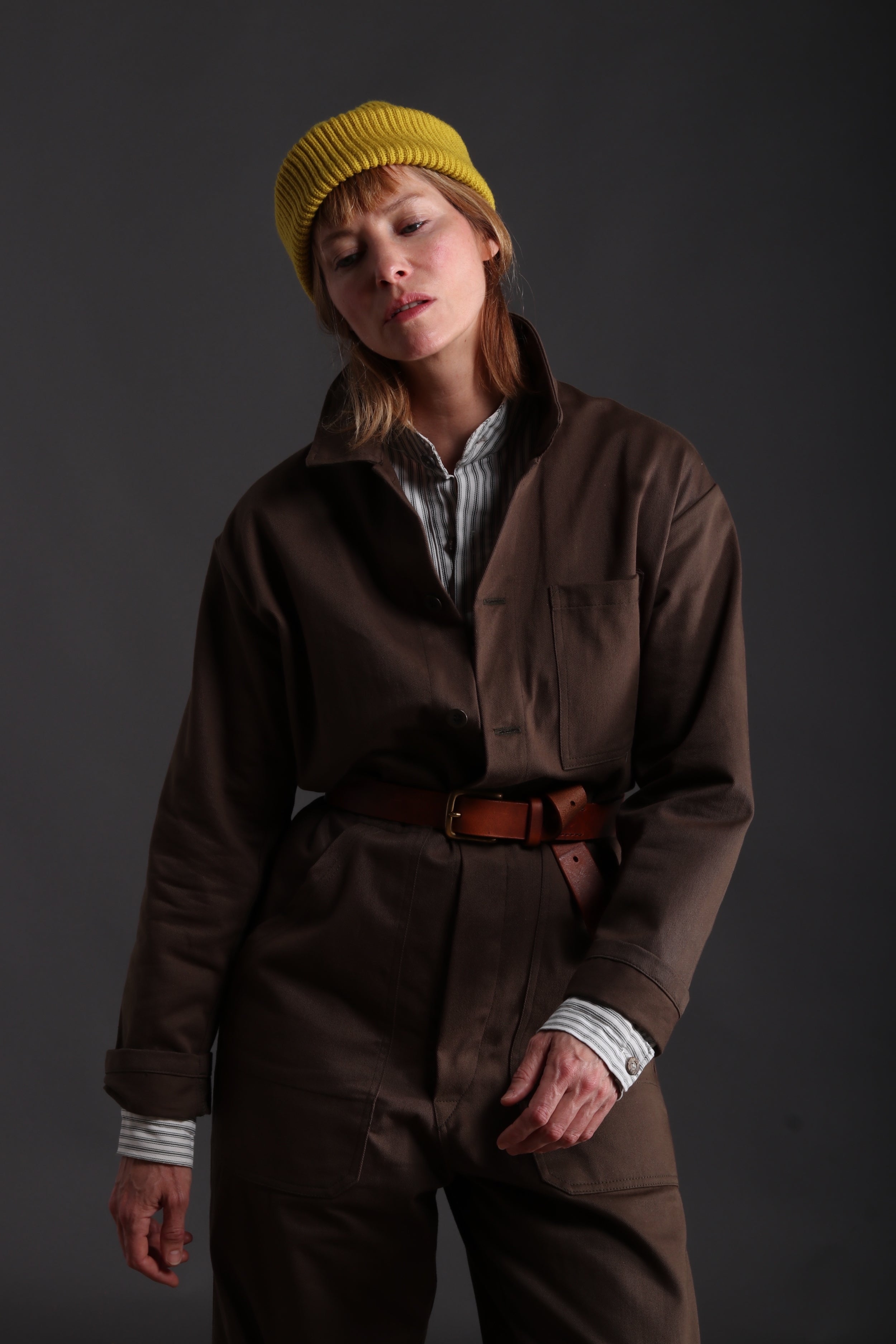 Sienna wears Carrier Company Boiler Suit in Olive Drill with Collarless Work Shirt in Ticking, Wool Hat and Chestnut Leather Belt