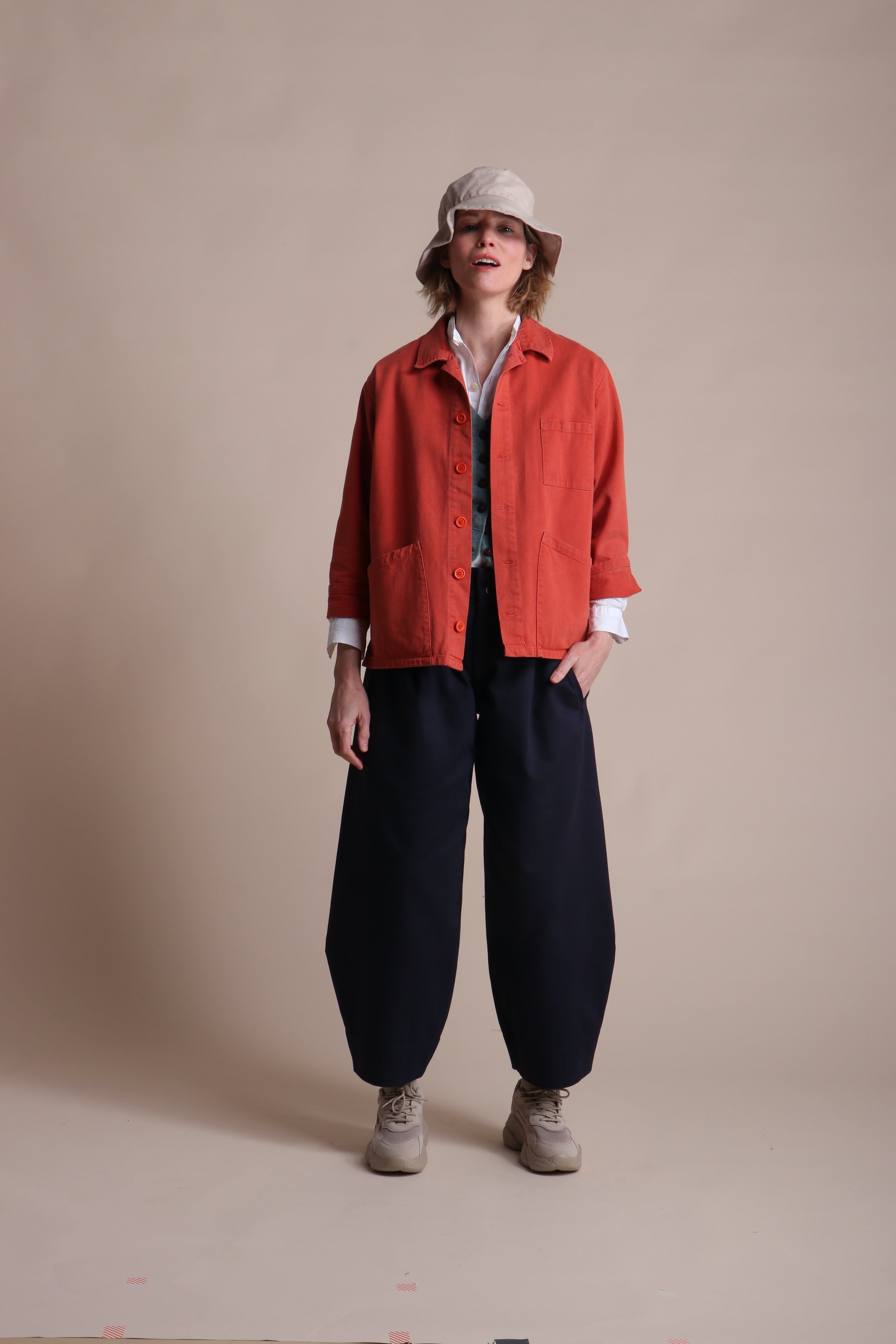 Woman wearing Carrier Company Dutch trouser In Navy Cotton Drill, Orange Norfolk Work Jacket and Cotton Sun Hat