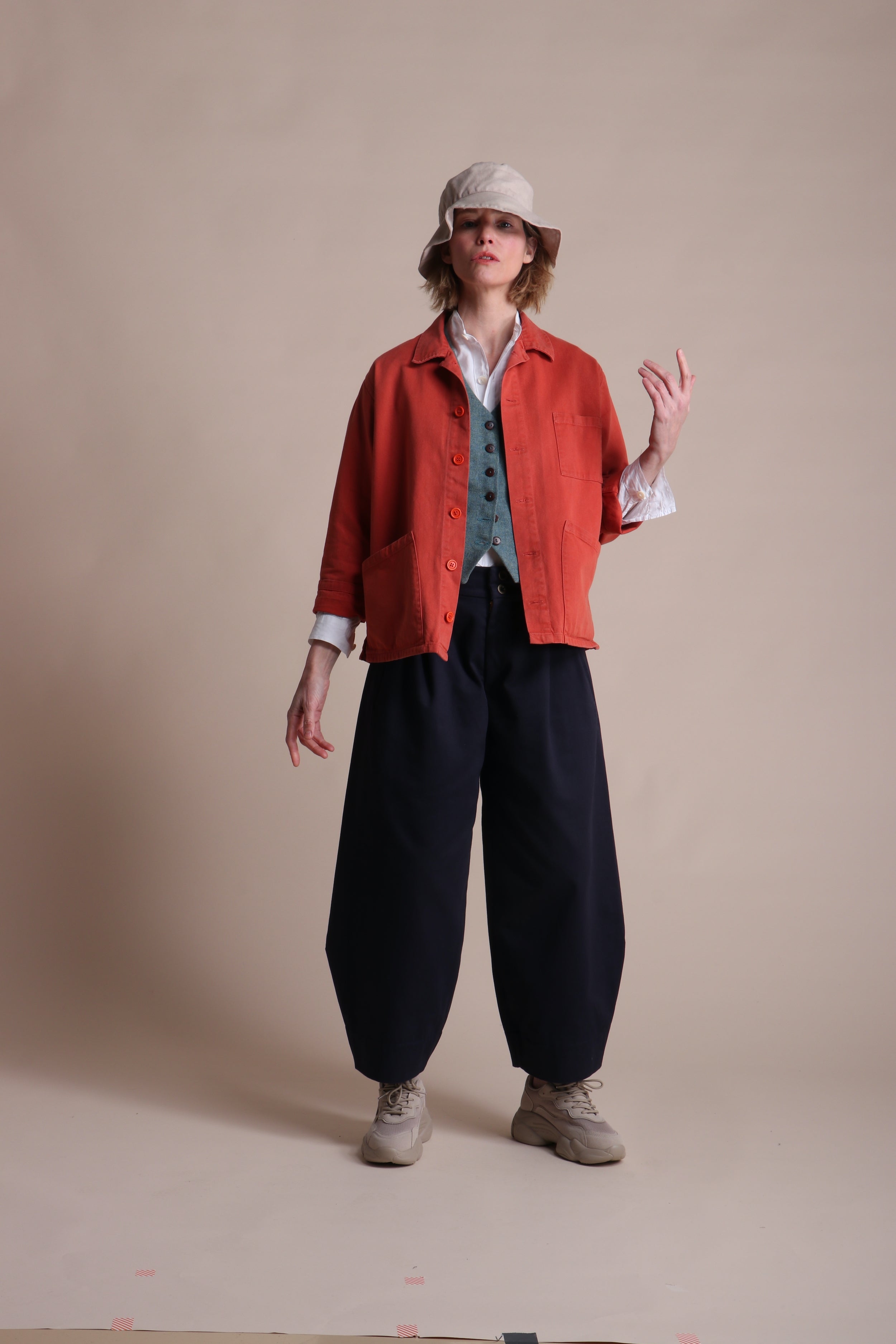 Woman wearing Carrier Company Dutch trouser In Navy Cotton Drill, Work Jacket in Orange and Cotton Sun Hat