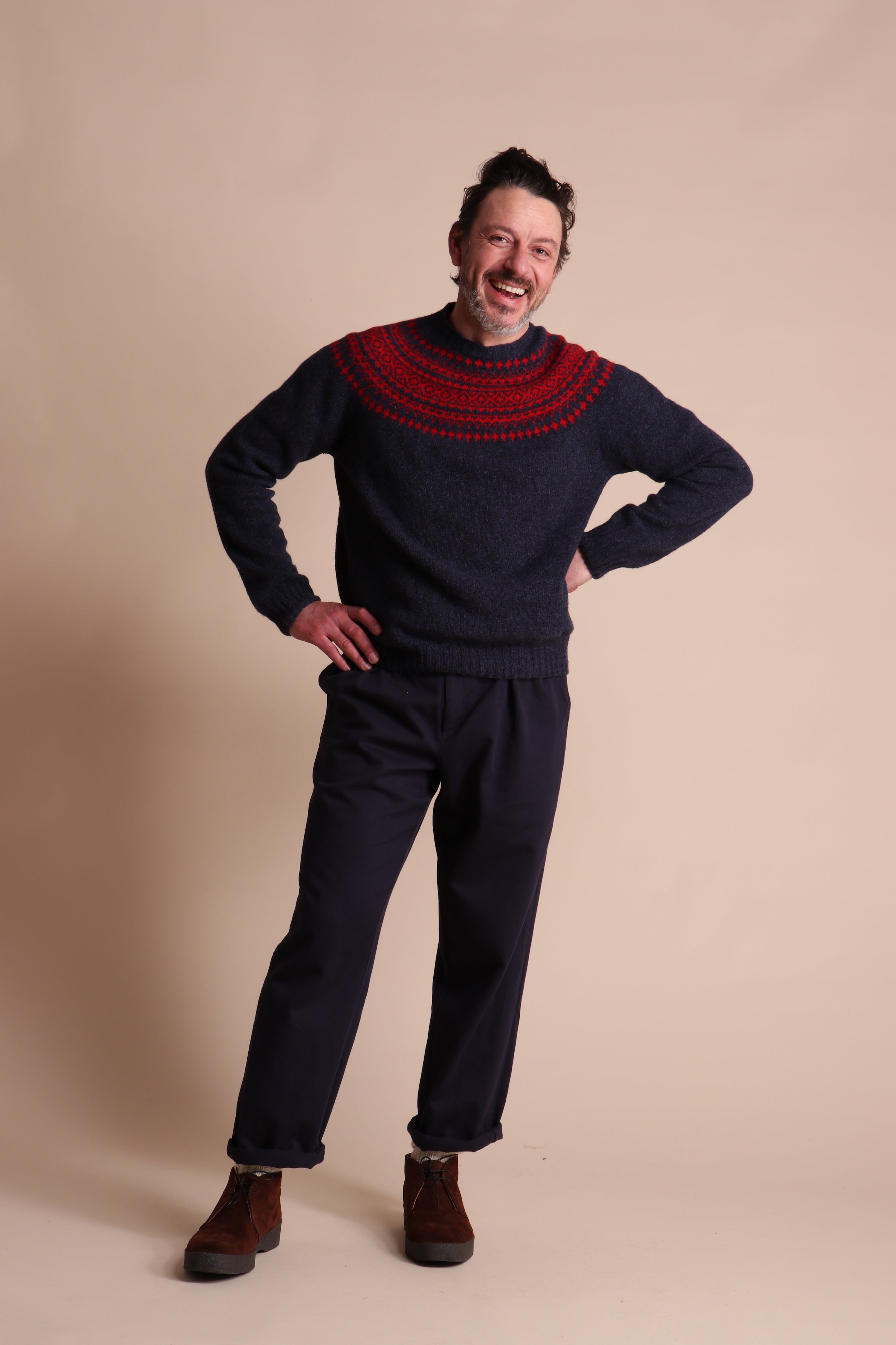 Man wears Carrier Company Shetland Lambswool Yoke Jumper in Ruby & Navy with Classic Trouser and Wool hat