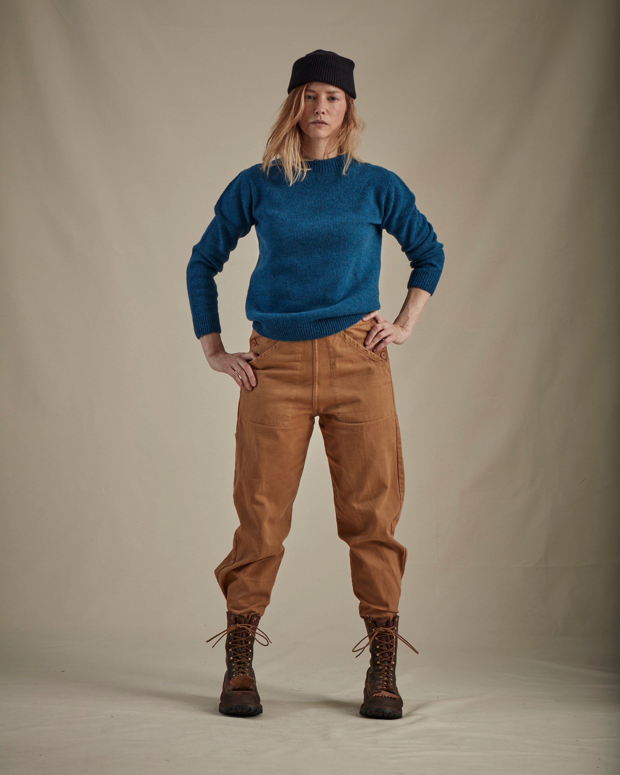 Woman wears Carrier Company Wool Hat in Navy  with Lambswool Jumper and Women's Work Trouser in Tan