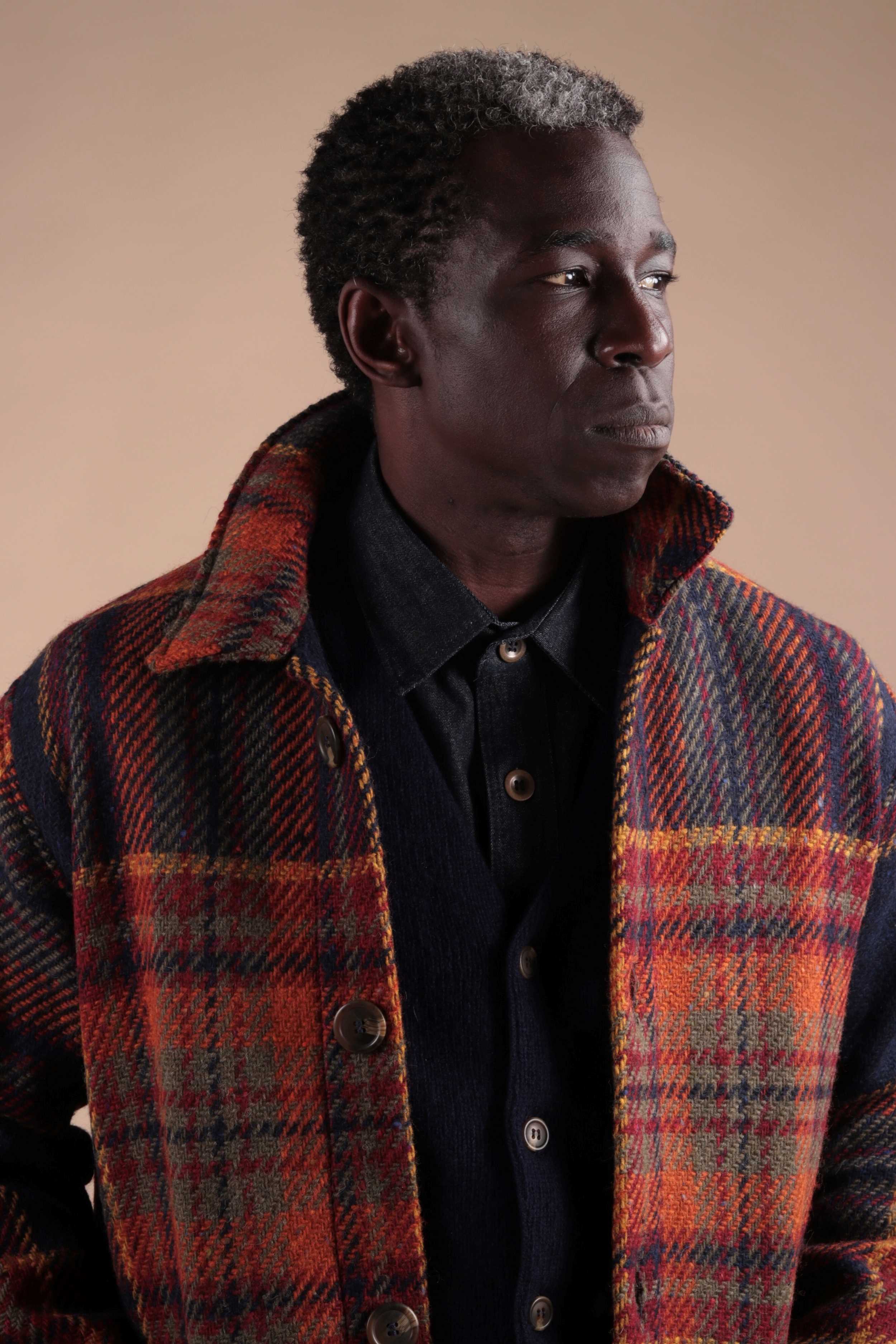 Man wears Celtic Wool Jacket in Navy and Rust with Wool Collar Shirt, Navy Cardigan and Tan Classic Trousers