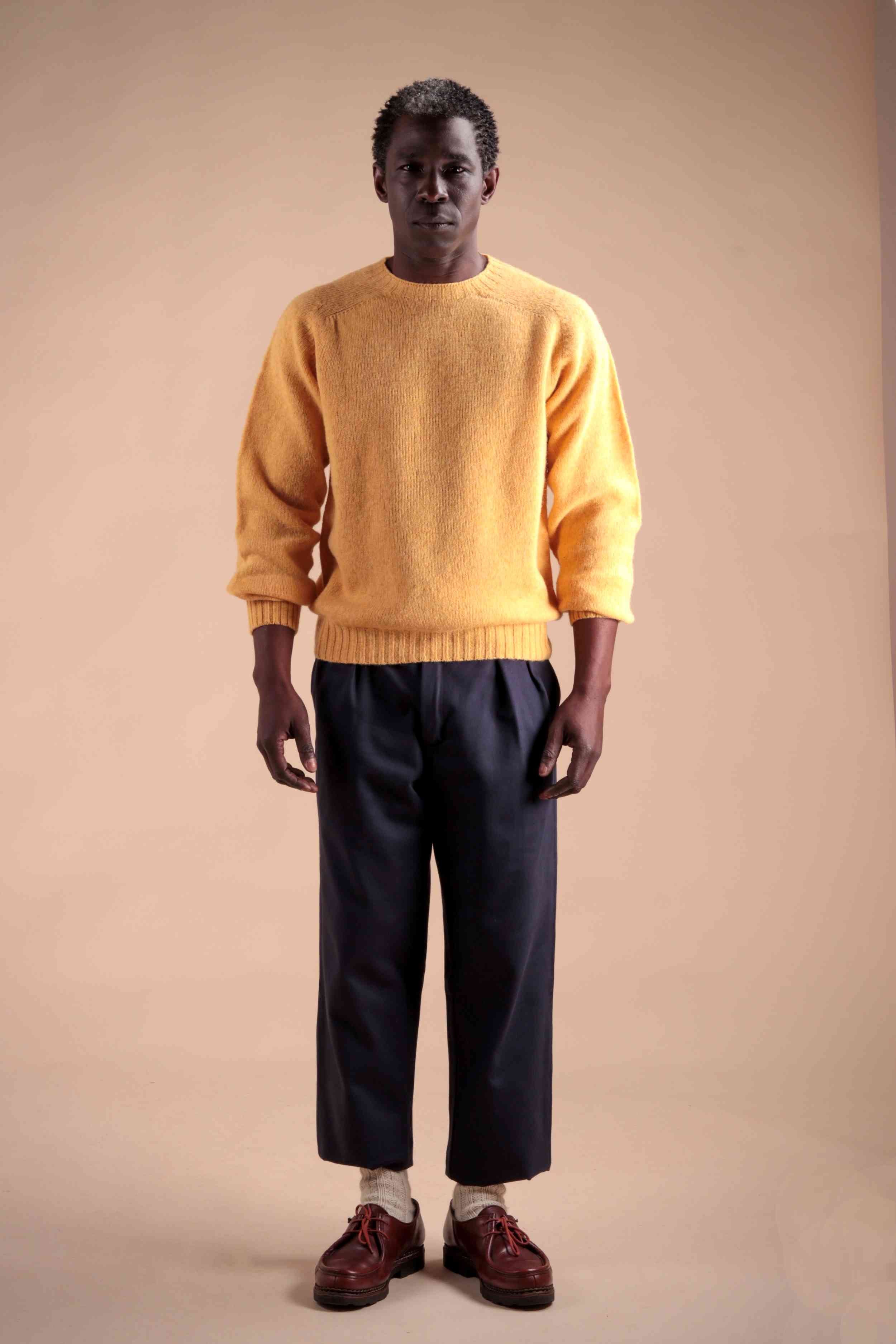 Man wearing Carrier Company Shetland Lambswool Jumper in Chamomile with Navy Classic Trousers