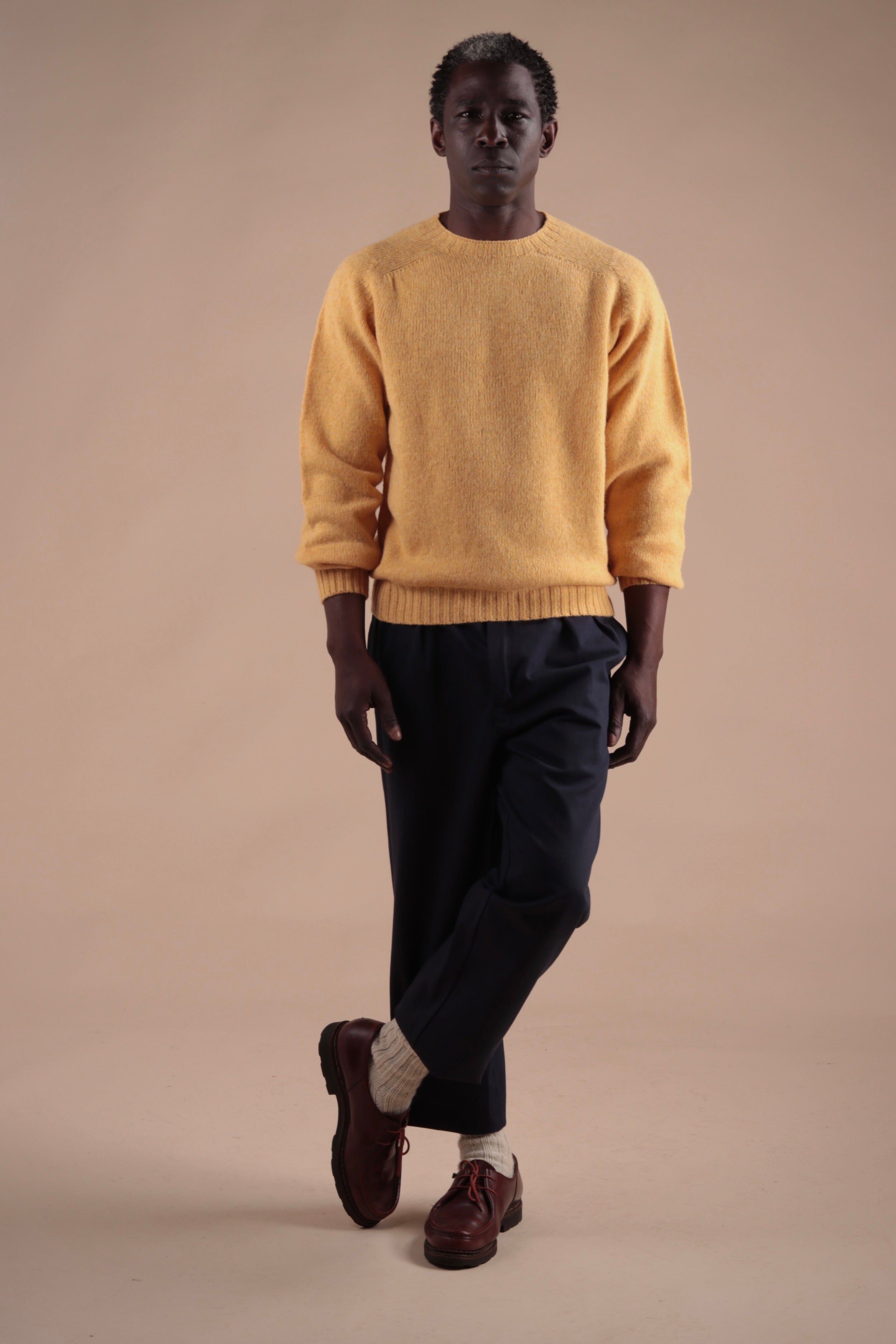 Man wearing Carrier Company Shetland Lambswool Jumper in Chamomile with Navy Classic Trousers and Wool Socks