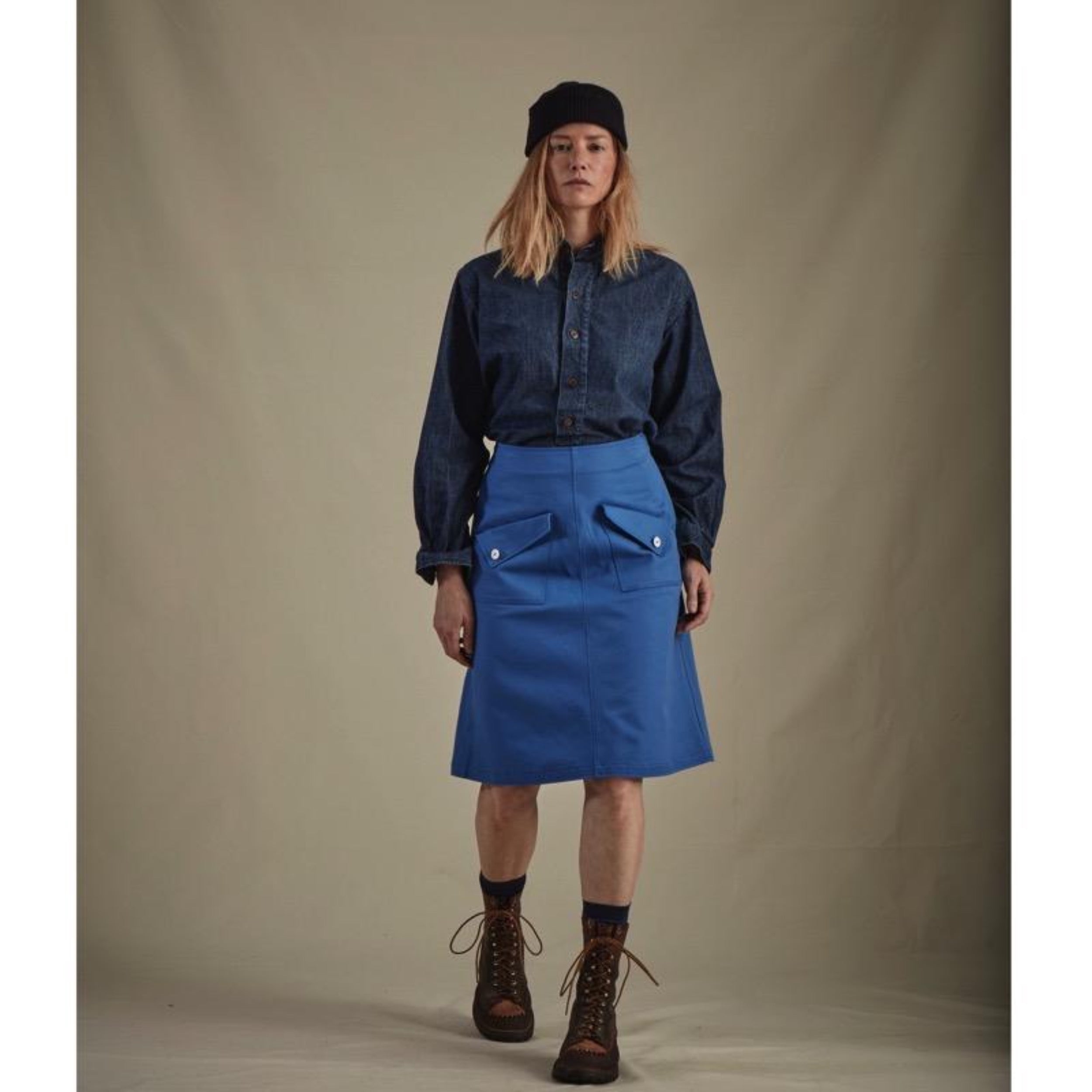 Woman wears Carrier Company Mum Skirt in Norfolk Sky Blue with Denim Work Shirt