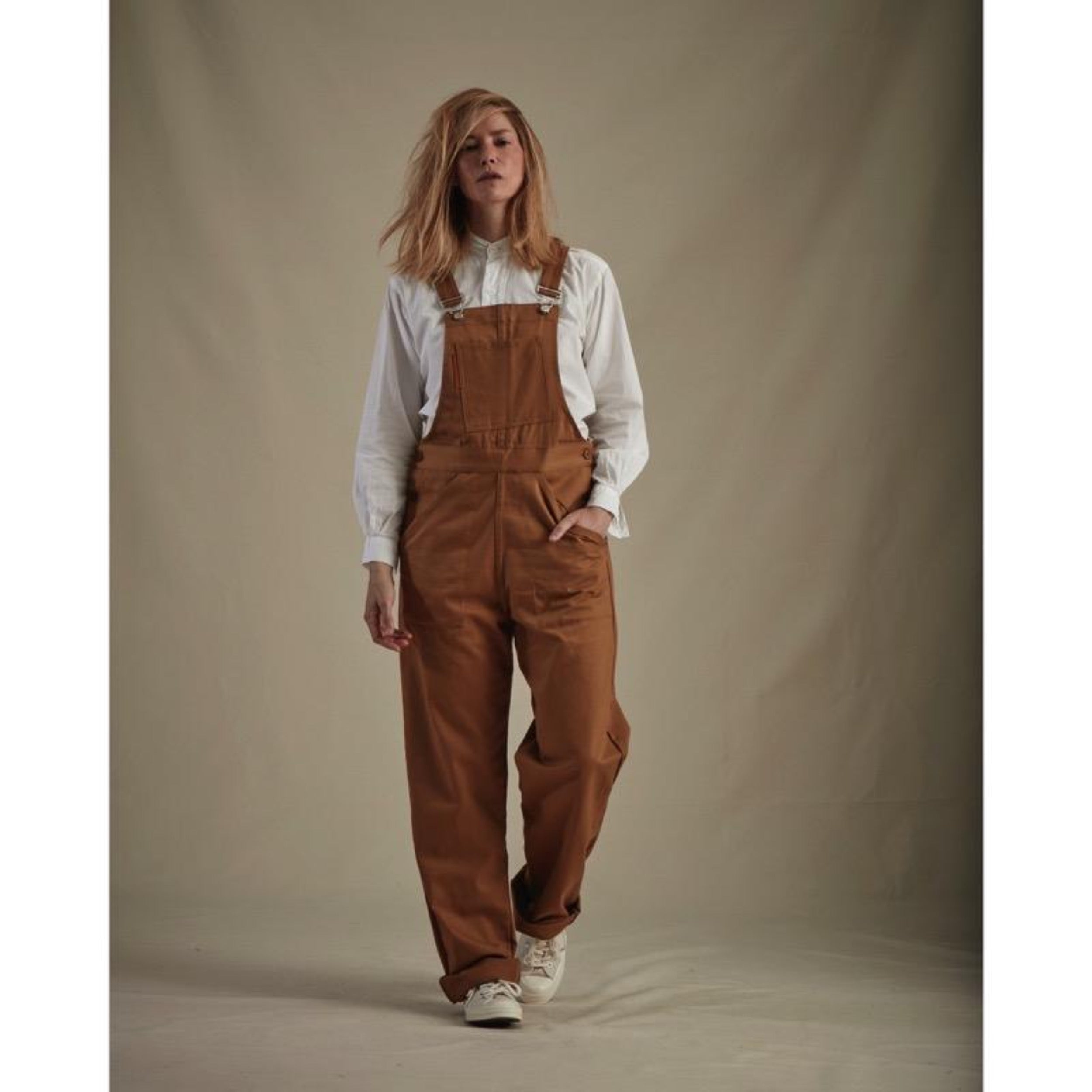 Woman wears Carrier Company Women's Dungarees in Tan with Lightweight Collarless Shirt